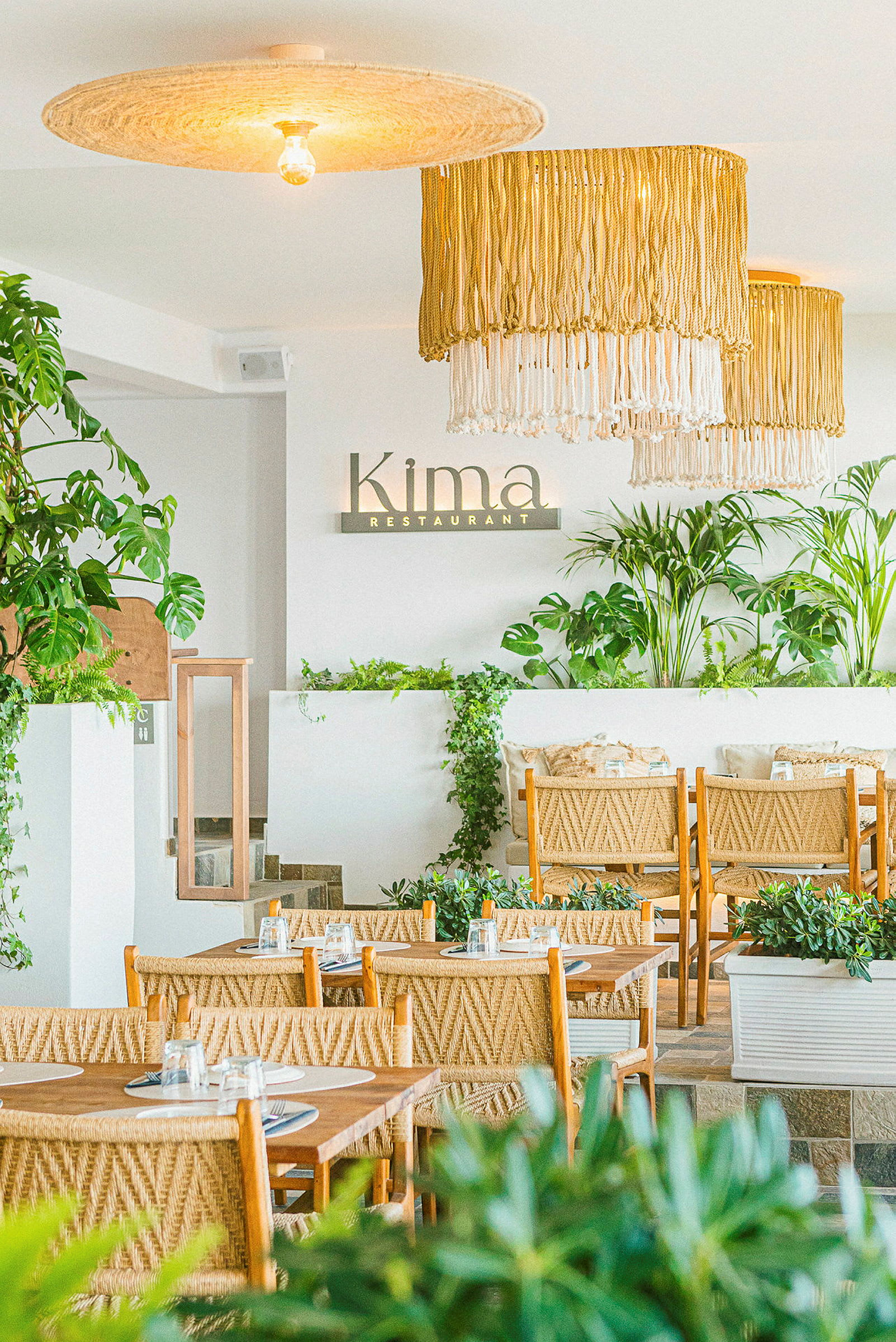 Billede af indretningen på en restaurant med grønne planter og rotting-inspirerede møbler. (AI-genereret tekst)