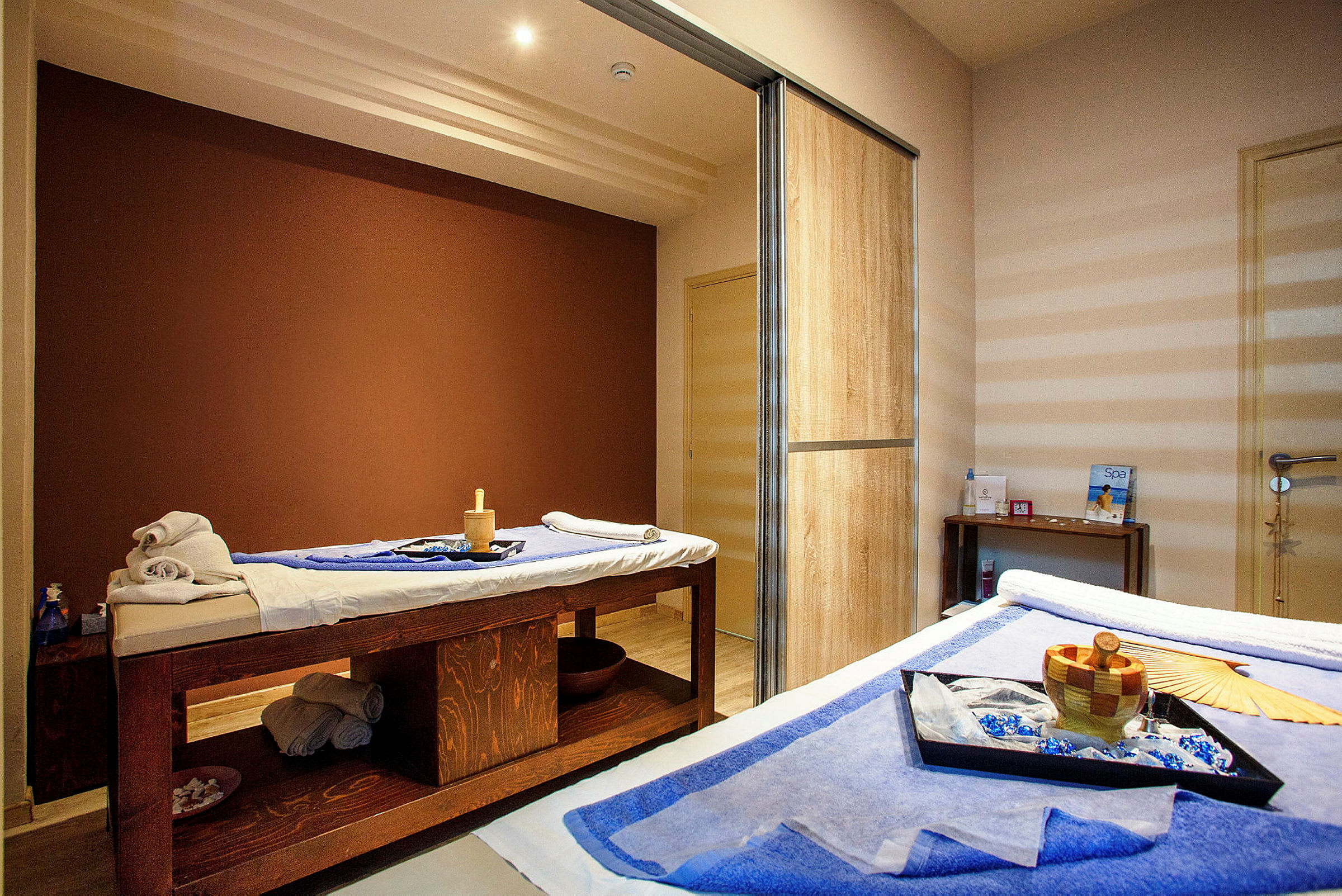 Et rum med terapeutiske behandlingsborde dækket med håndklæder og spa-tilbehør. (AI-genereret tekst)