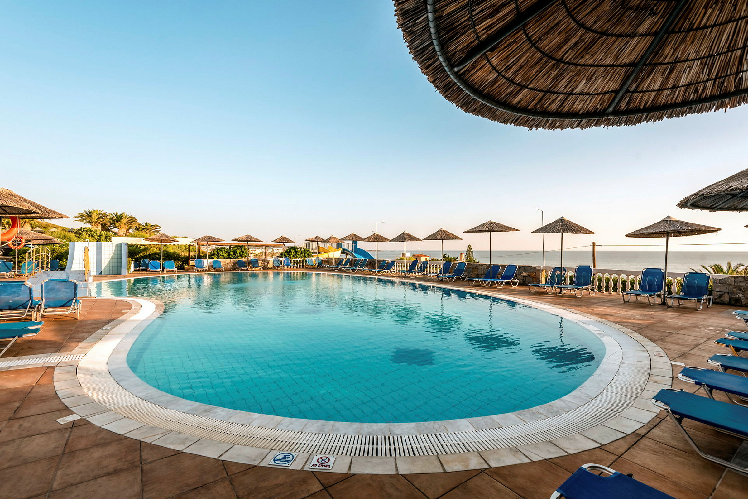 Udendørs swimmingpool med liggestole og parasoller omkring. (AI-genereret tekst)