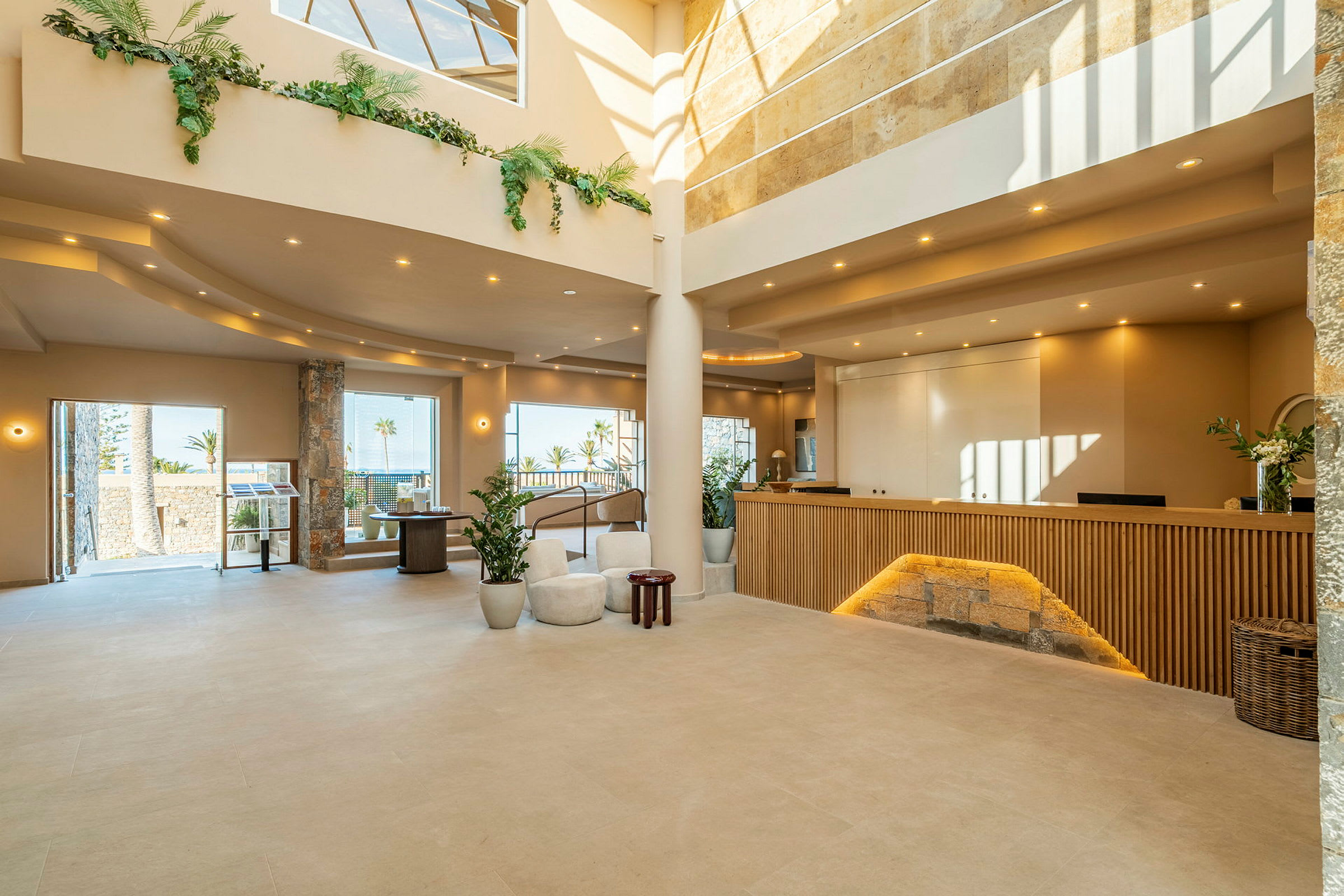 En moderne hotellobby med en receptionsskranke og store vinduer, der lukker dagslys ind. (AI-genereret tekst)