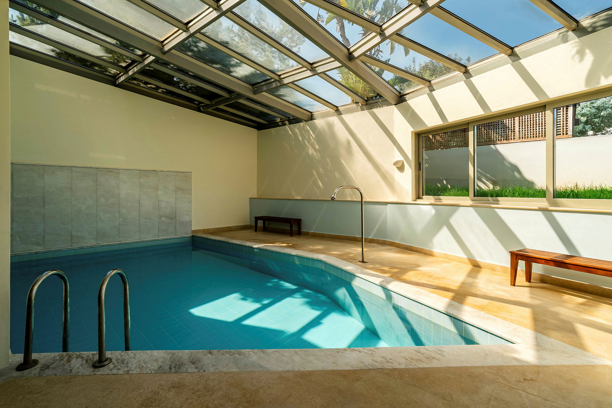 Indendørs pool med glasvægge og -tag, der lader naturligt lys komme ind. (AI-genereret tekst)