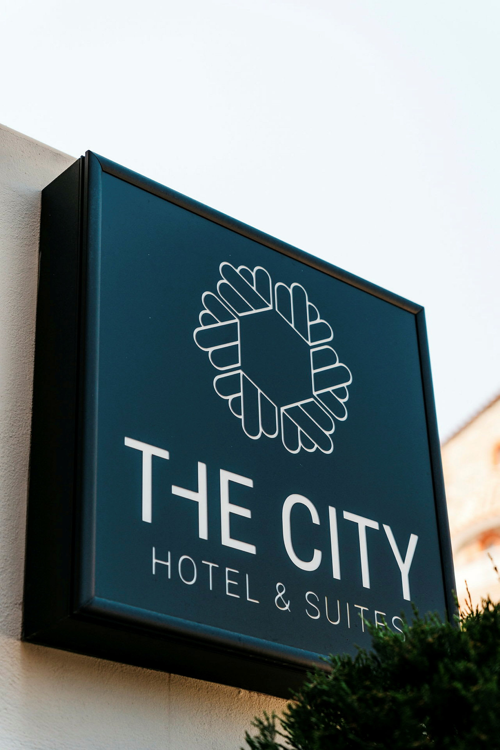 Skilt for "The City Hotel & Suites" mod lys baggrund. (AI-genereret tekst)