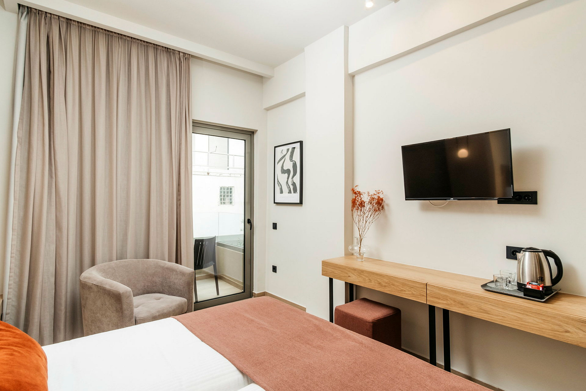 Hotelværelse med seng, skrivebord, stol og altan. (AI-genereret tekst)