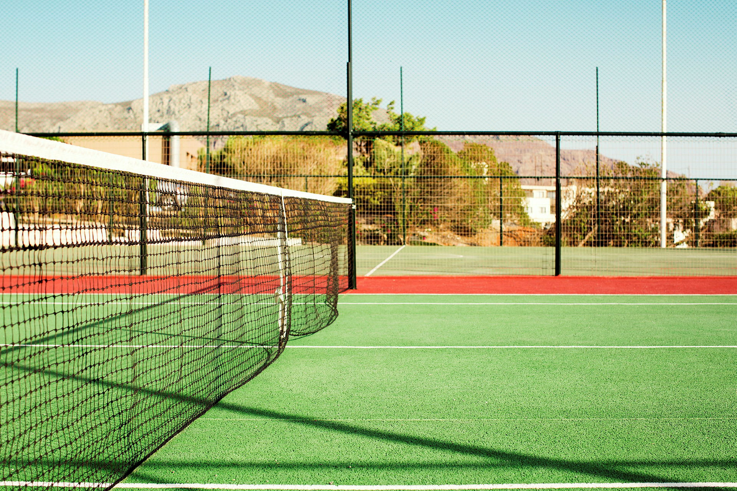 En tennisbane med net og hegn. (AI-genereret tekst)