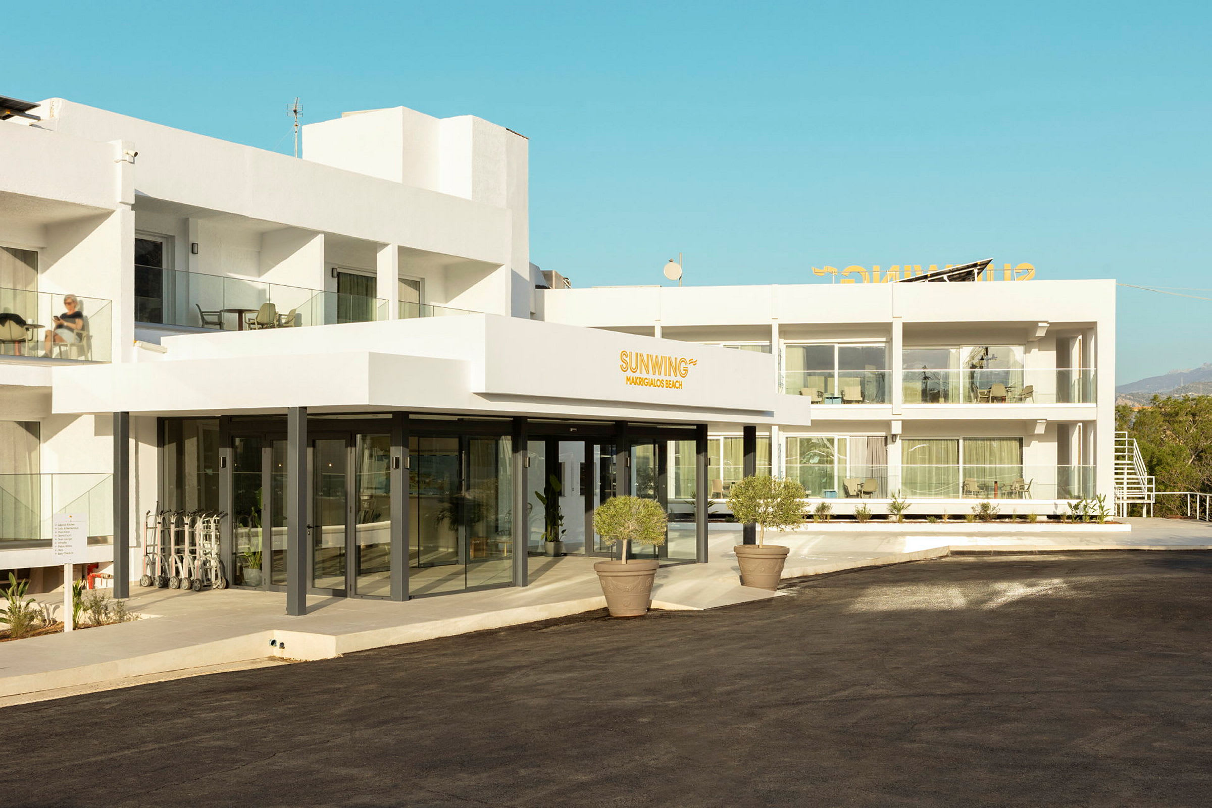 Facade af et moderne hotelkompleks med hvide vægge og gangsti foran. (AI-genereret tekst)