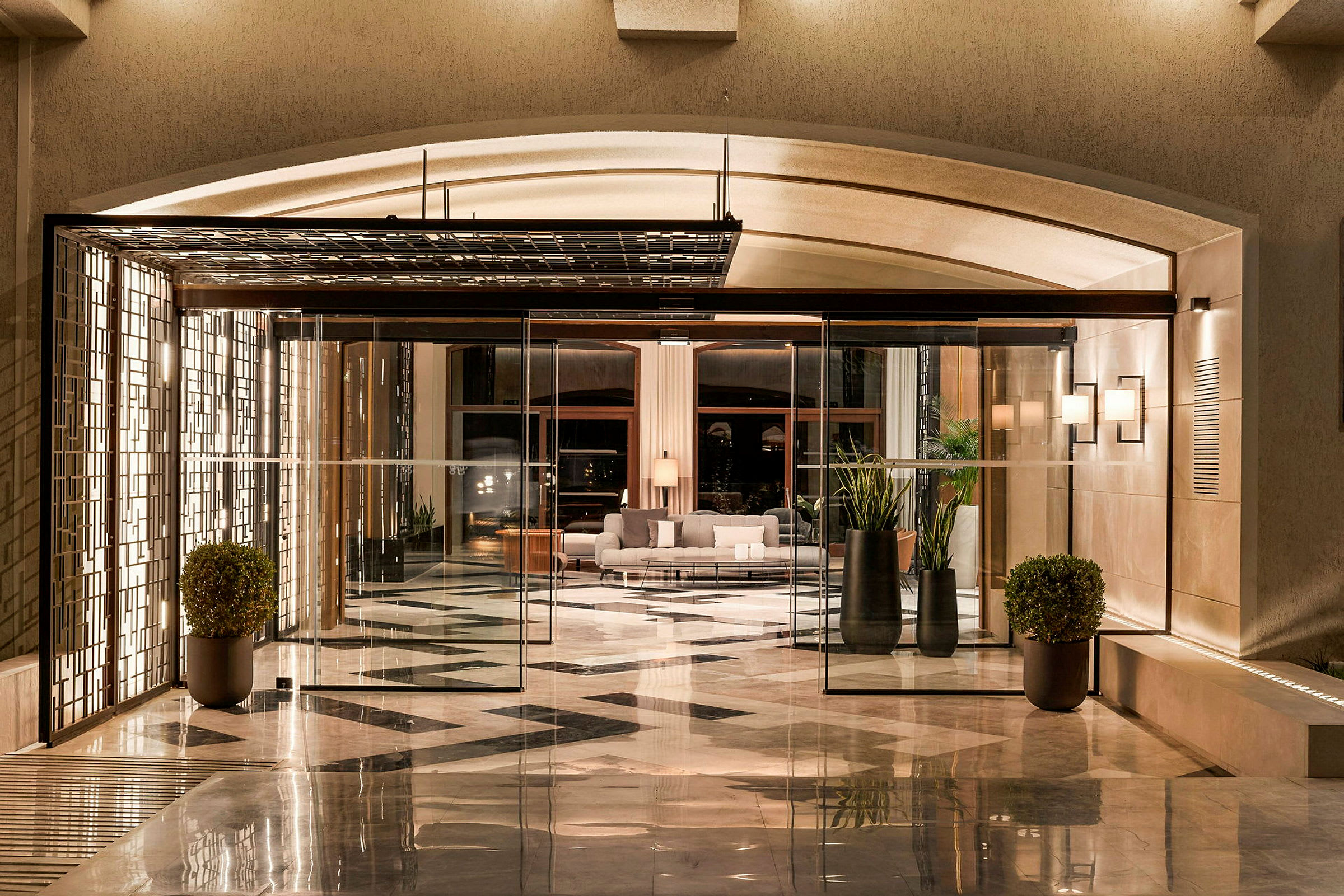 Billede af en hotellobby med glasdøre, moderne møbler og marmorgulvdesign. (AI-genereret tekst)