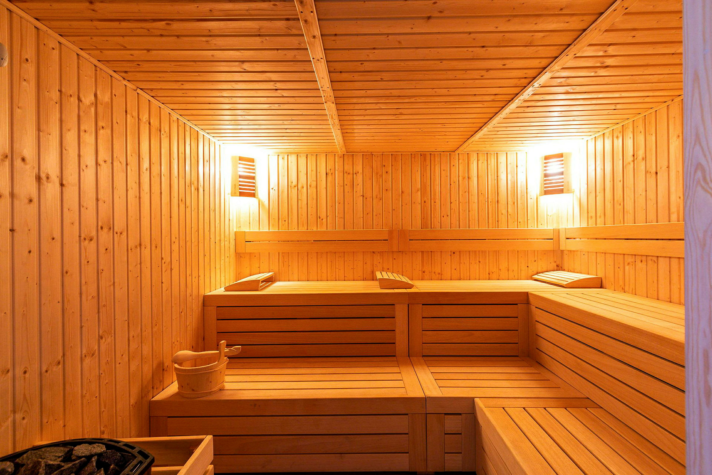 Interiøret af en træbeklædt sauna med siddebænke og en varmekilde. (AI-genereret tekst)