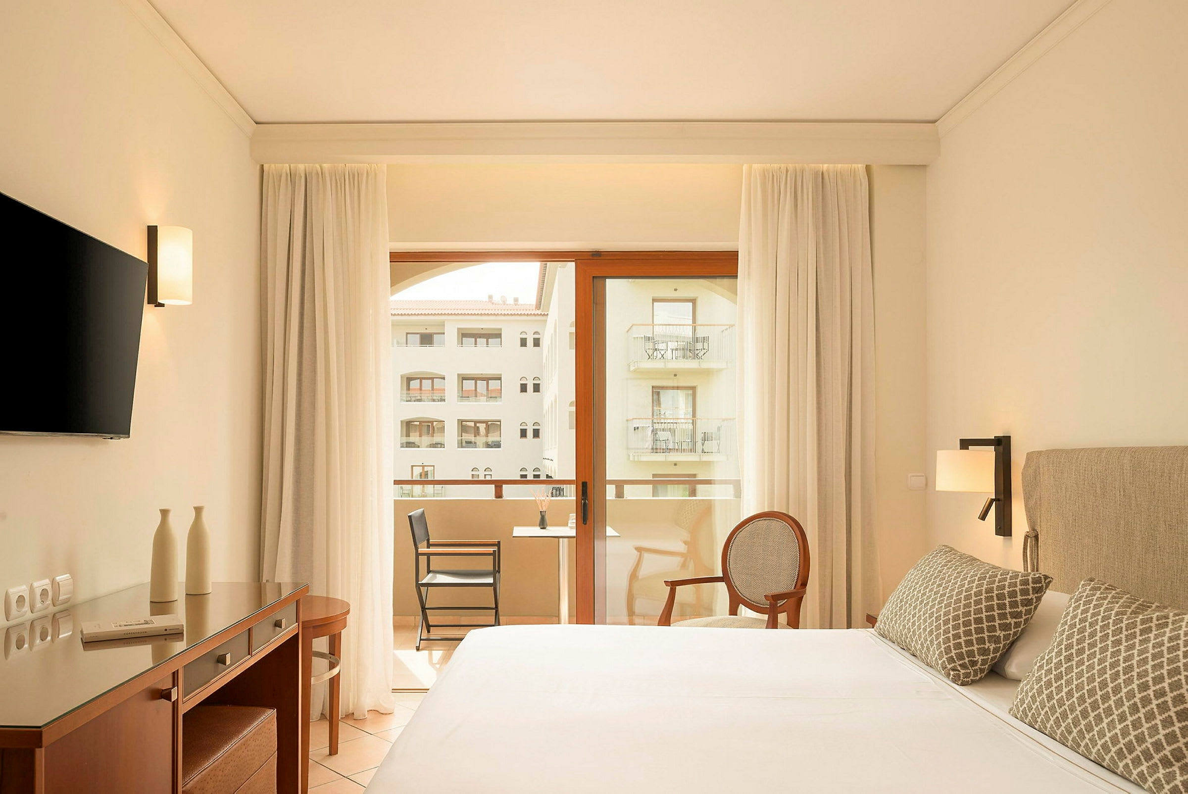Moderne hotelværelse med dobbeltseng, skrivebord, tv og altan med udsigt. (AI-genereret tekst)