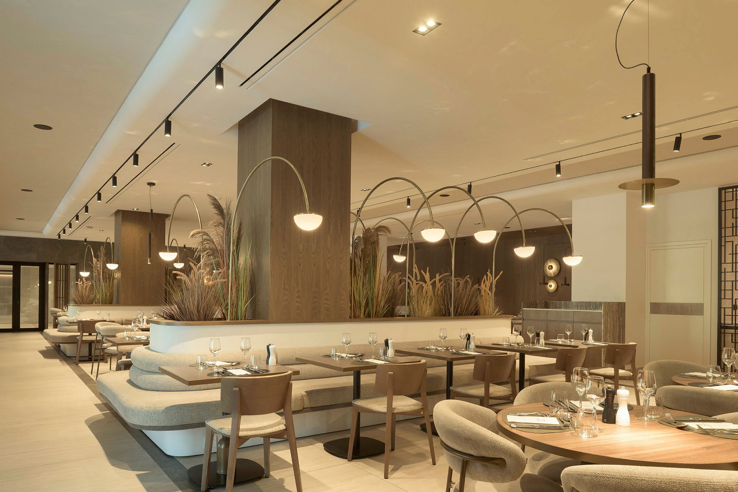 Interiør af en moderne restaurant med flere borde og stole, lys belysning og dekorative planter. (AI-genereret tekst)