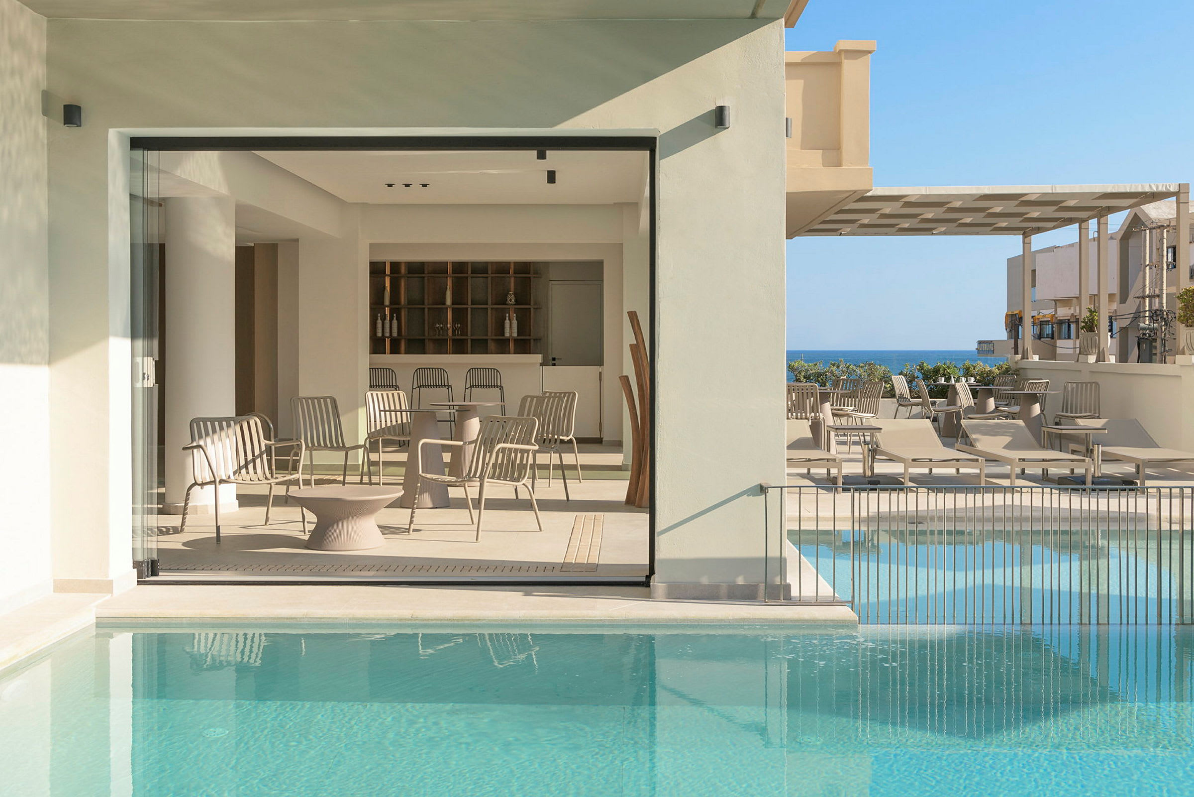 Moderne indrettet terrasse med swimmingpool, siddepladser og udsigt mod havet. (AI-genereret tekst)