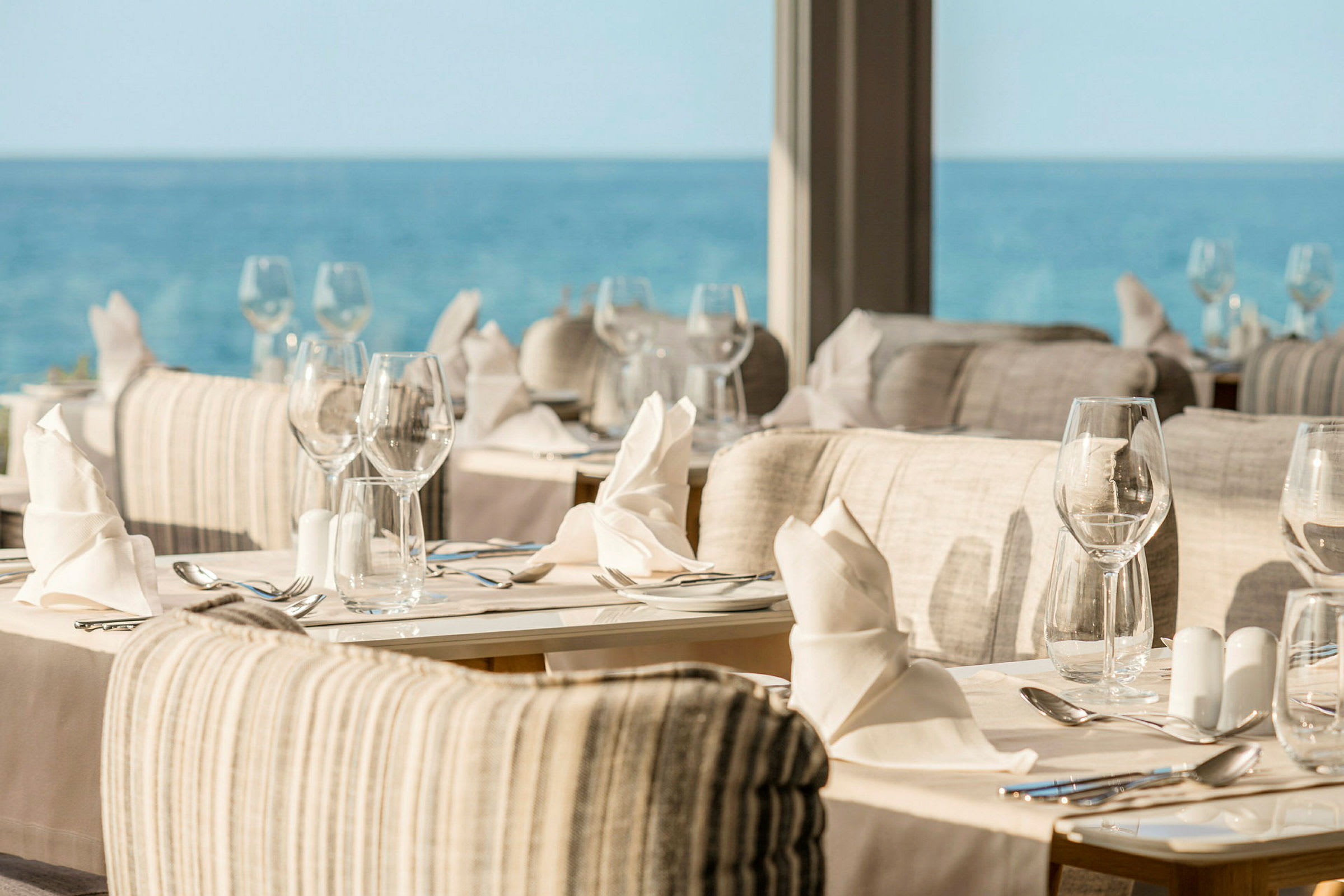 Restaurant med dækkede borde og udsigt over havet. (AI-genereret tekst)