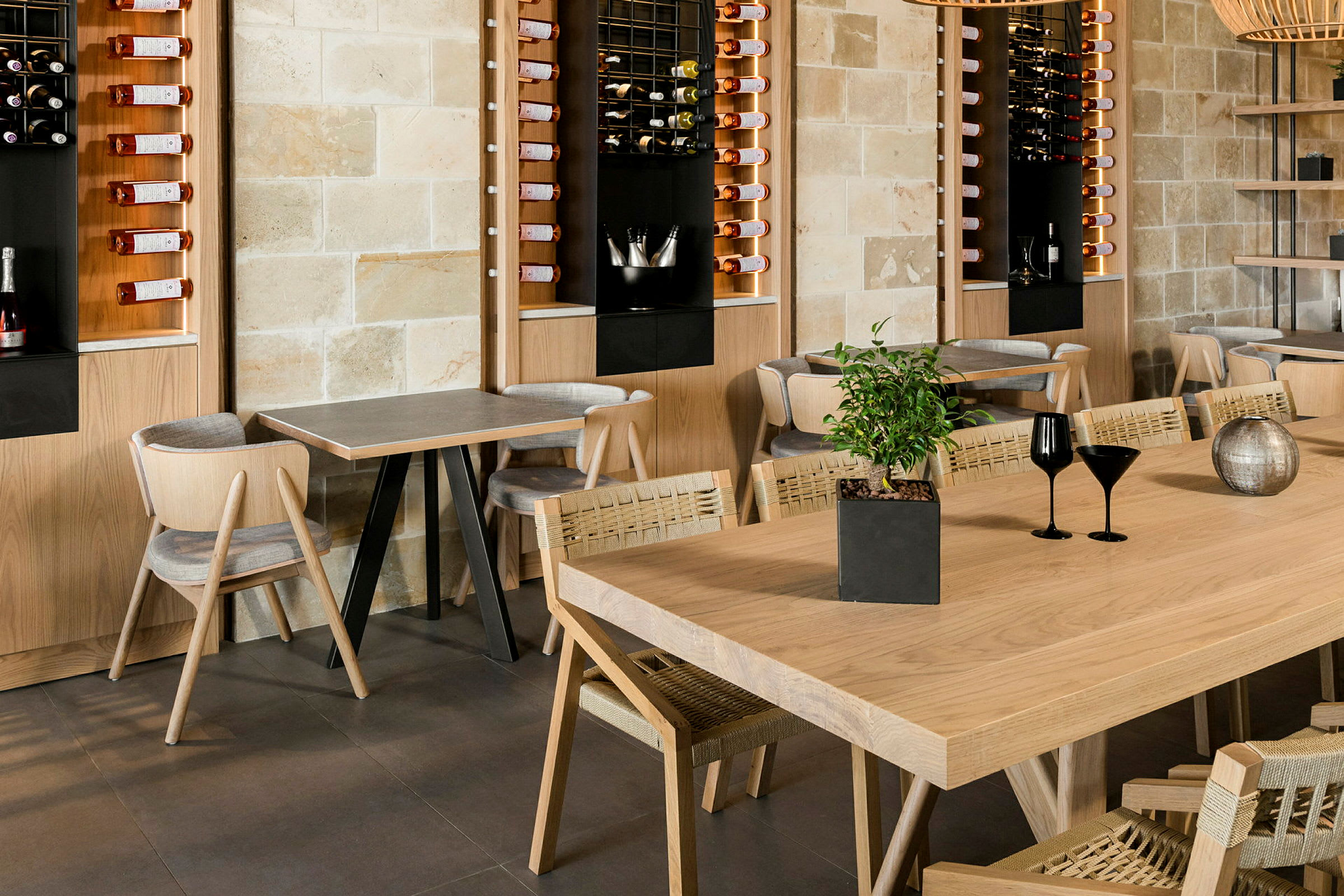 En moderne restaurant med træborde og stole samt vægopbevaring til vinflasker. (AI-genereret tekst)