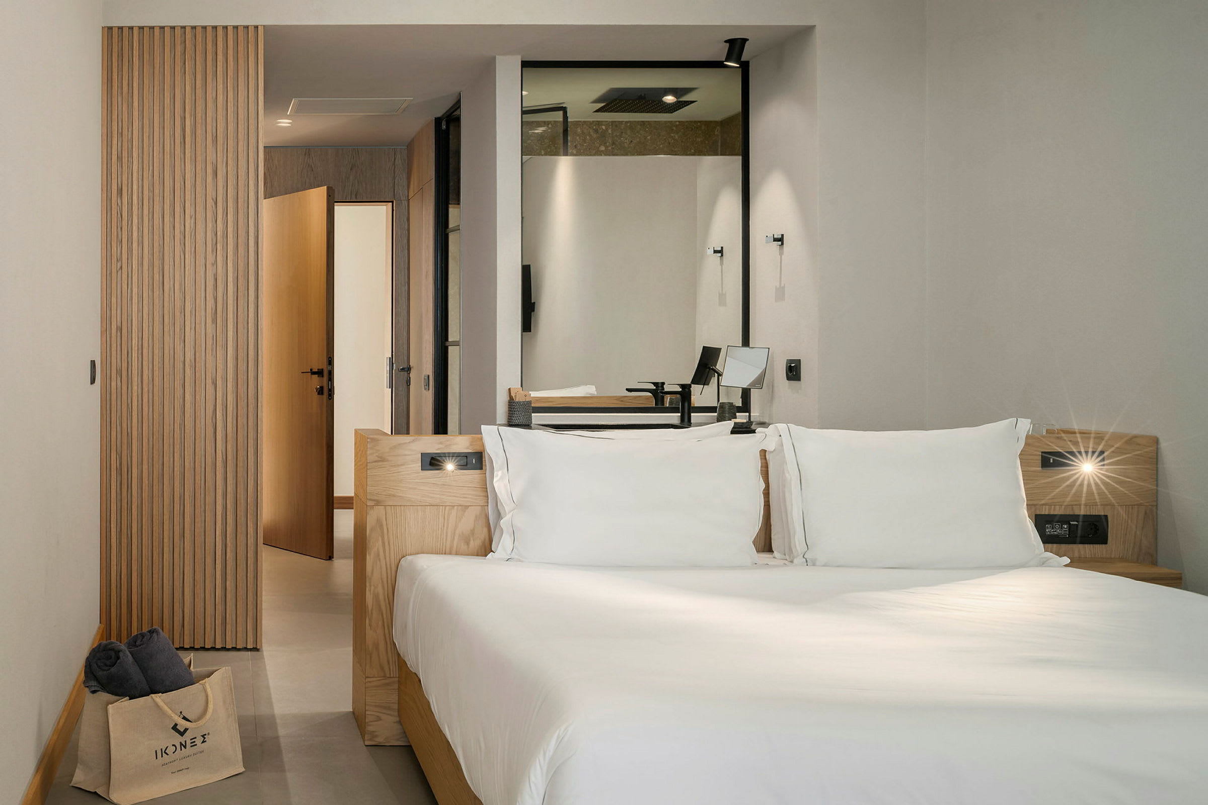 Moderne hotelværelse med en dobbeltseng, hovedsageligt indrettet med trædetaljer og med indsigt mod badeværelset. (AI-genereret tekst)