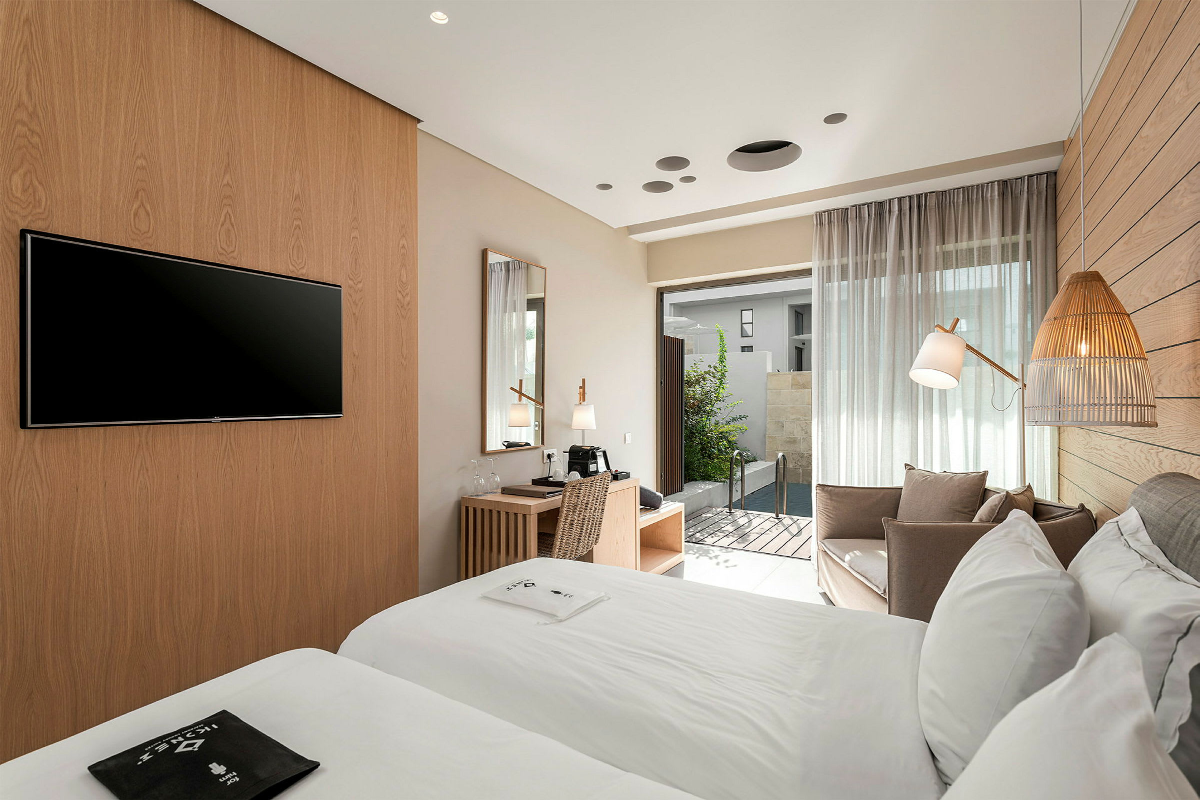 Hotelværelse med to senge, skrivebord og siddeområde. Dør der fører ud til lille pool. (AI-genereret tekst)