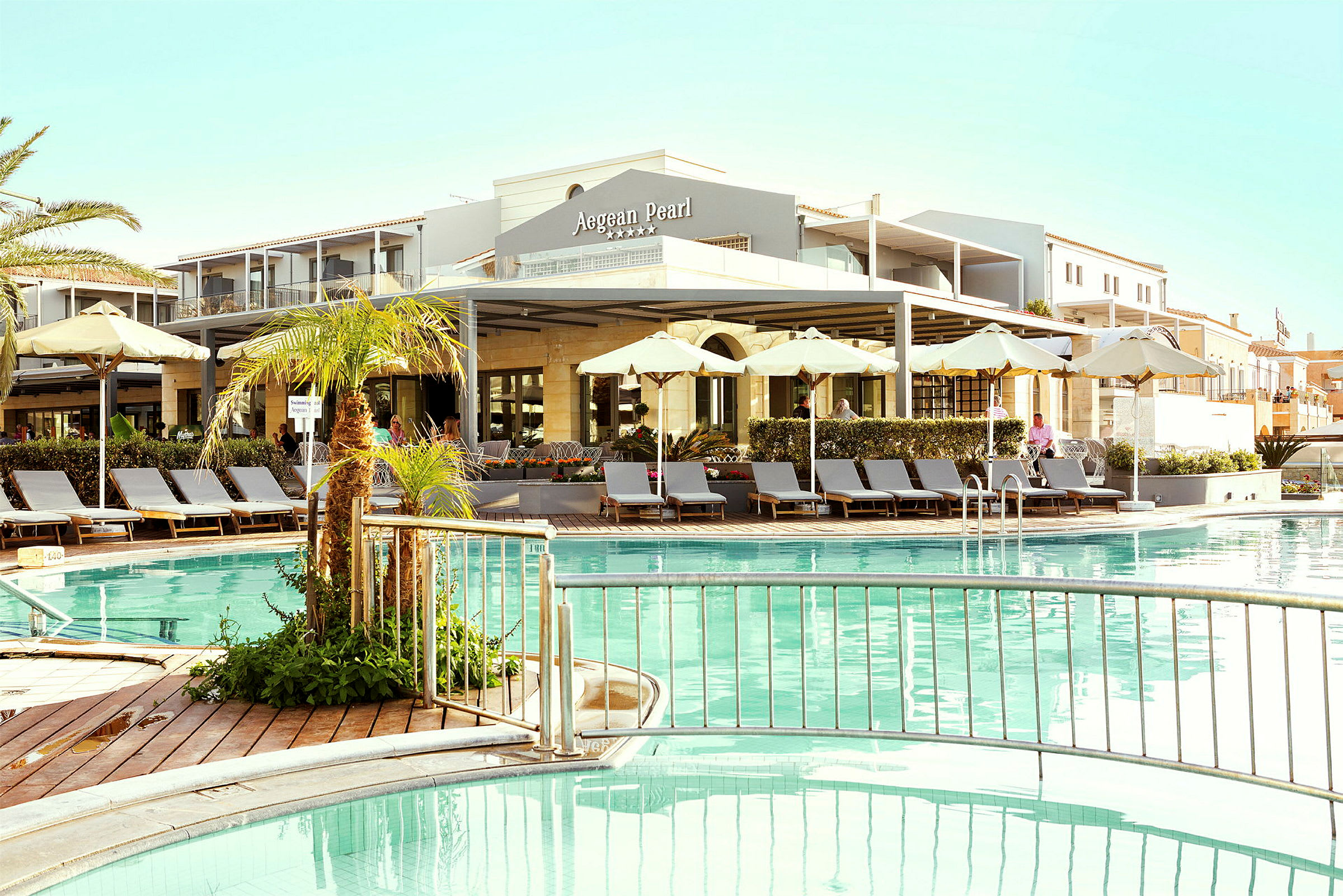 Hotel med udendørs pool, solsenge og parasoller. (AI-genereret tekst)