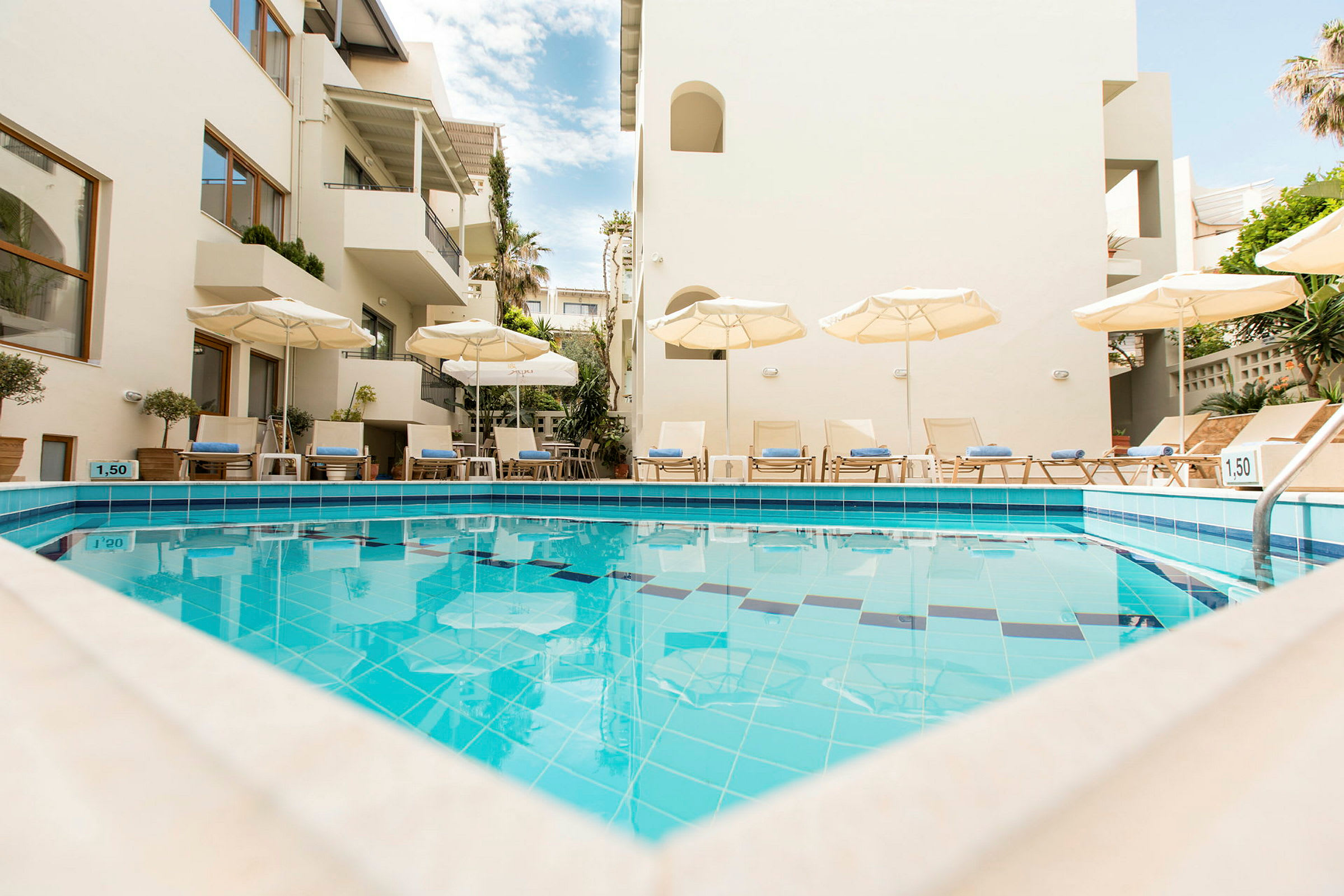 Udendørs swimmingpool med liggestole og parasoller ved et hotel. (AI-genereret tekst)