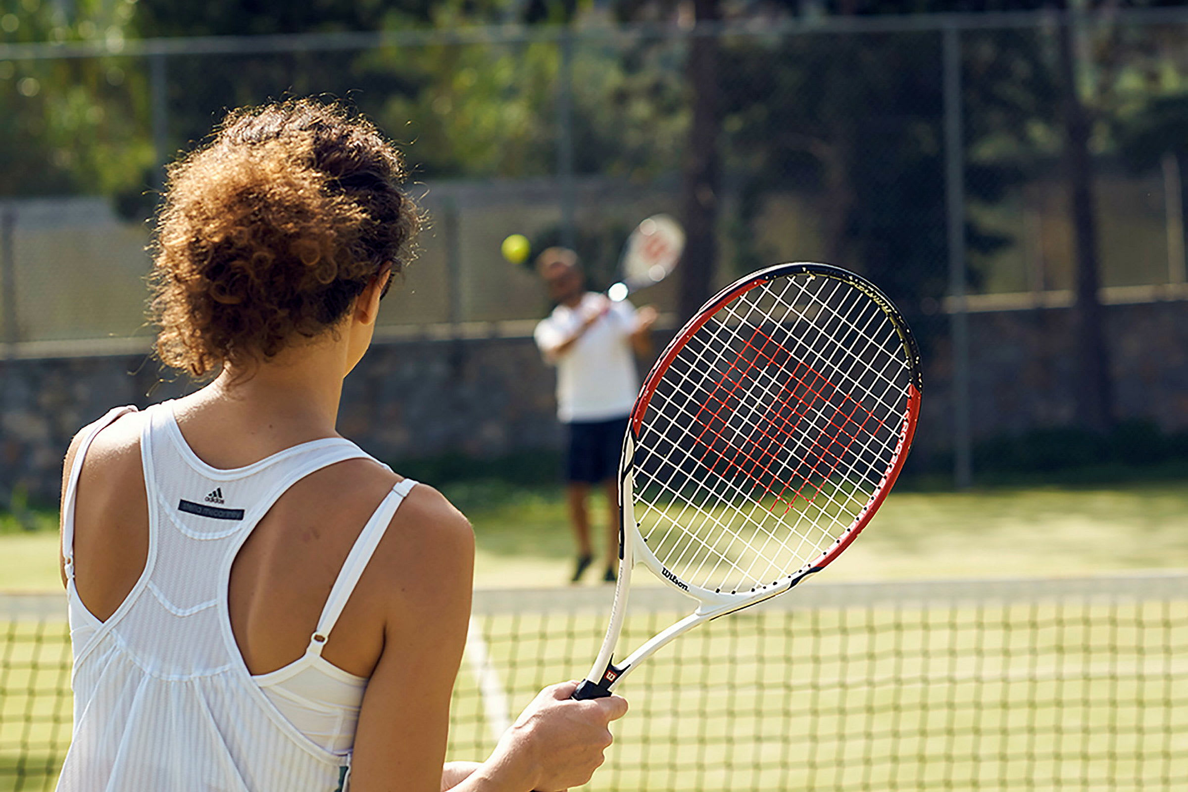 Person holder en tennisracket på en tennisbane. (AI-genereret tekst)
