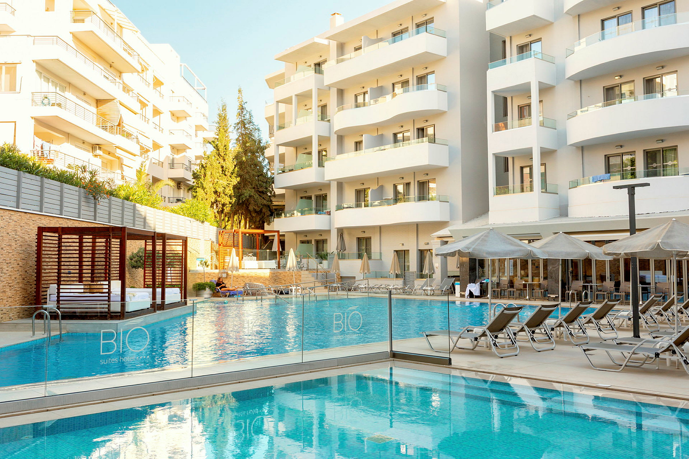 Billede af et hotel med en udendørs pool og liggestole foran bygningen. (AI-genereret tekst)