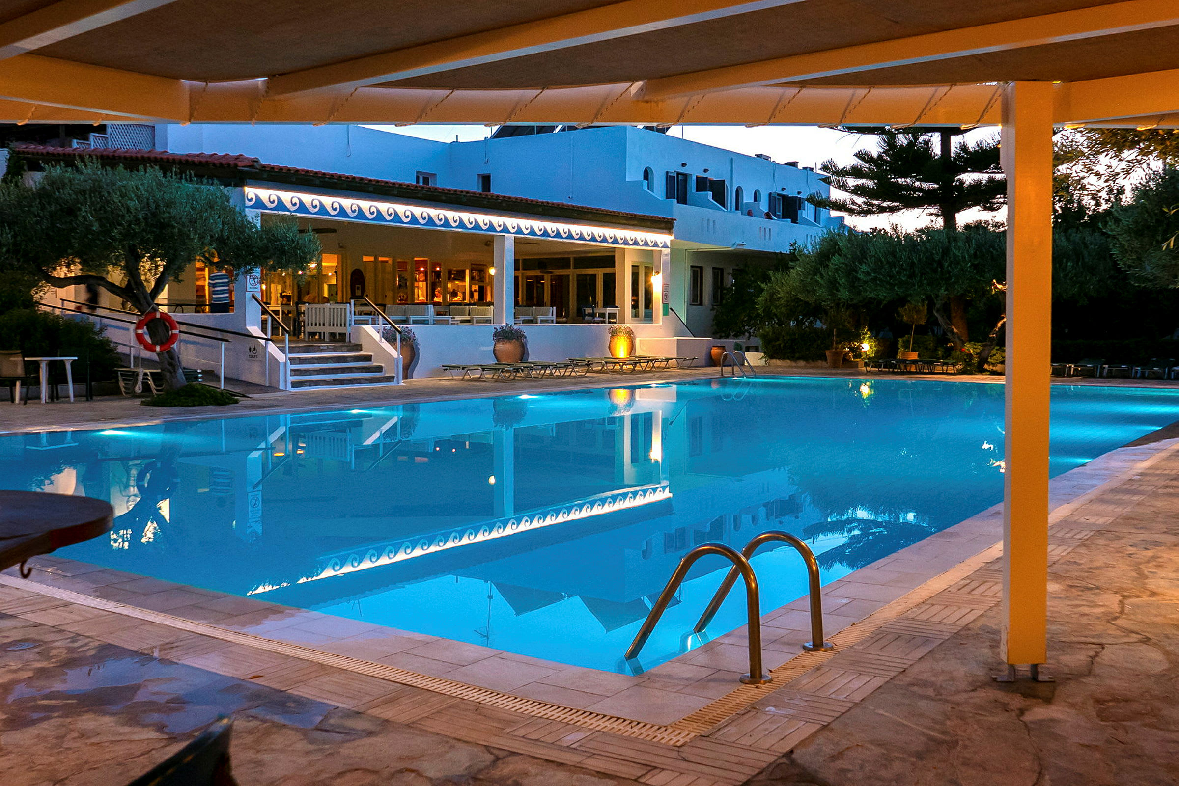 En oplyst pool ved et hotel om aftenen. (AI-genereret tekst)