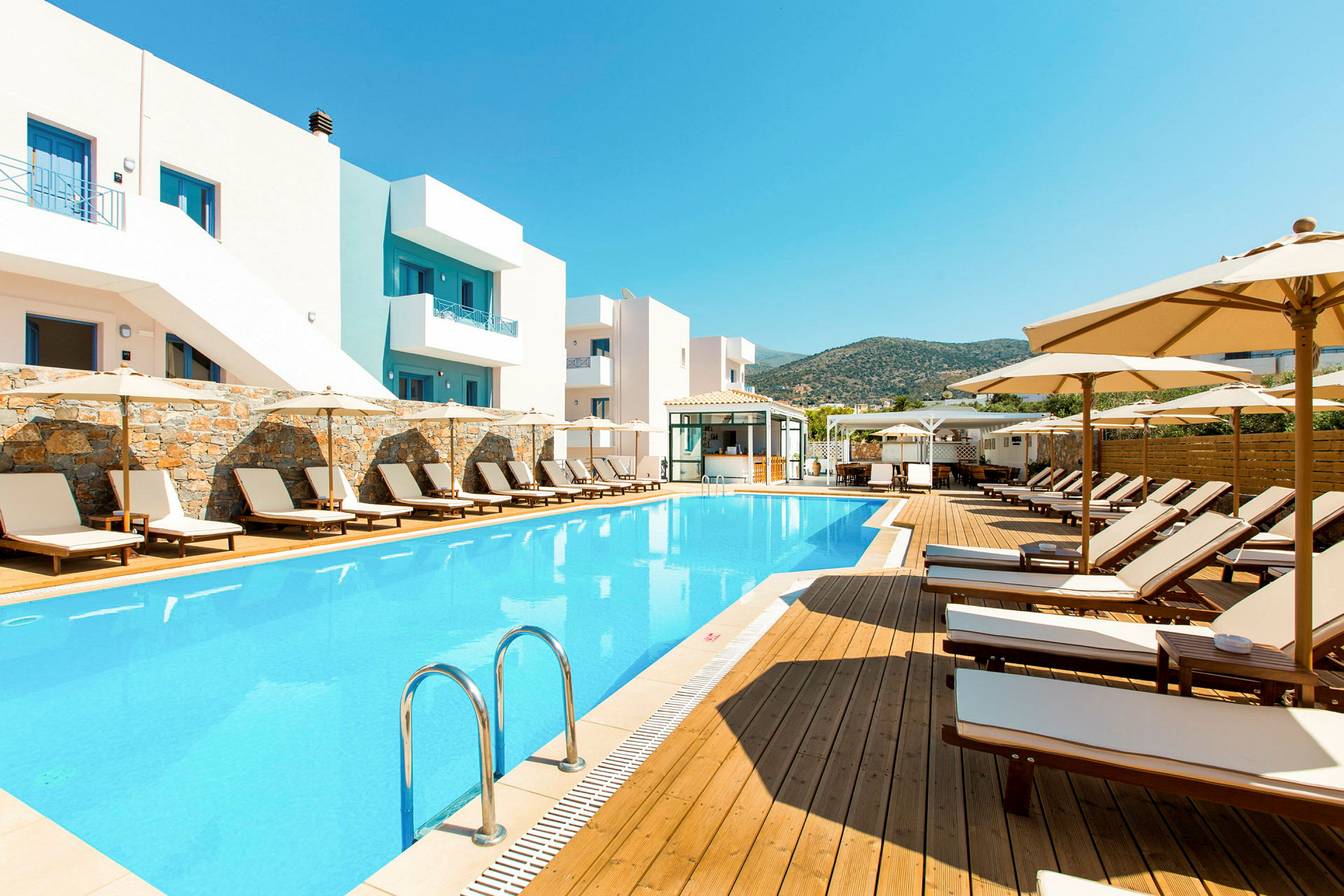 Udendørs swimmingpool og liggestole ved hotelbygning. (AI-genereret tekst)