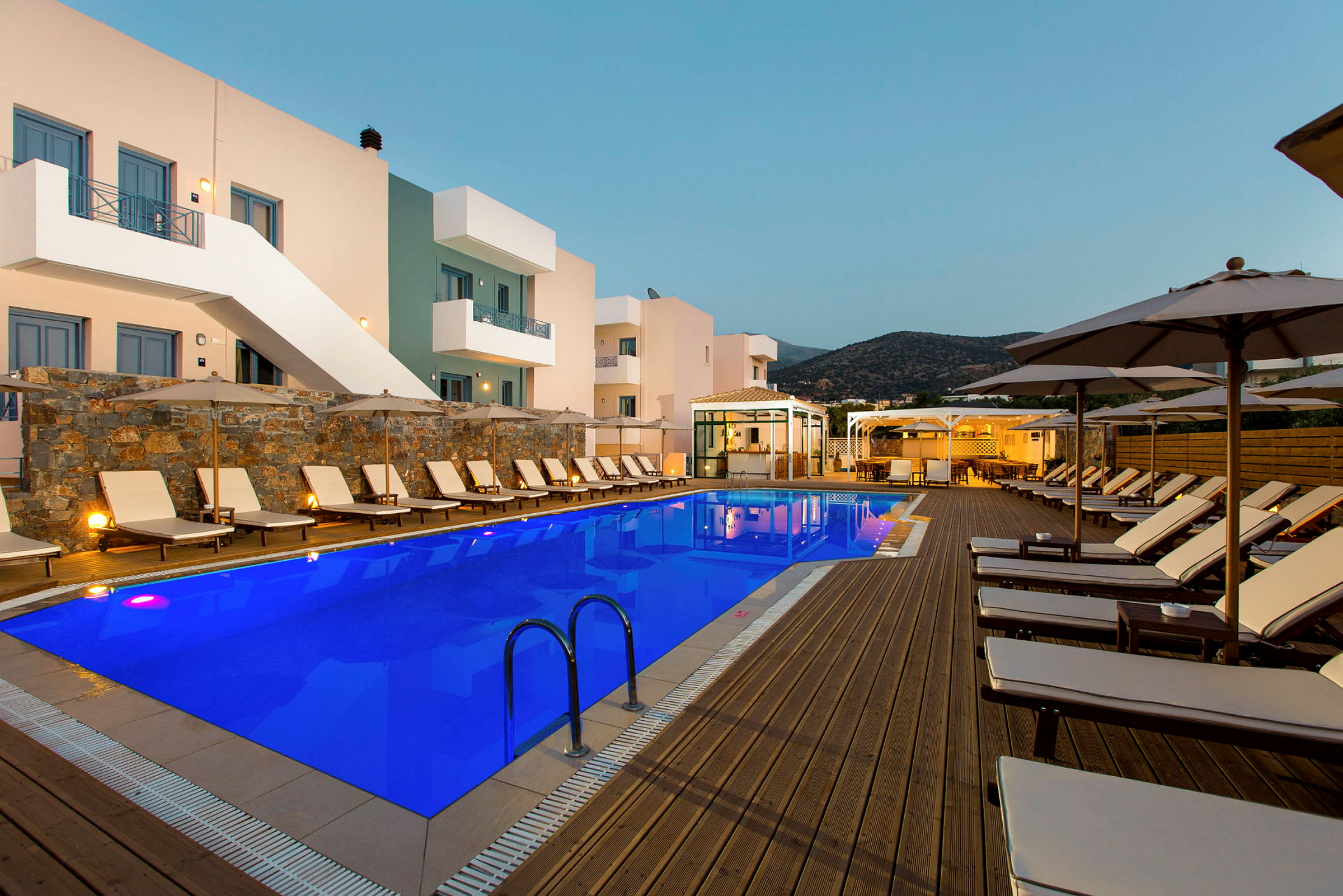 En pool på et hotel med omkringliggende liggestole og parasoller. (AI-genereret tekst)