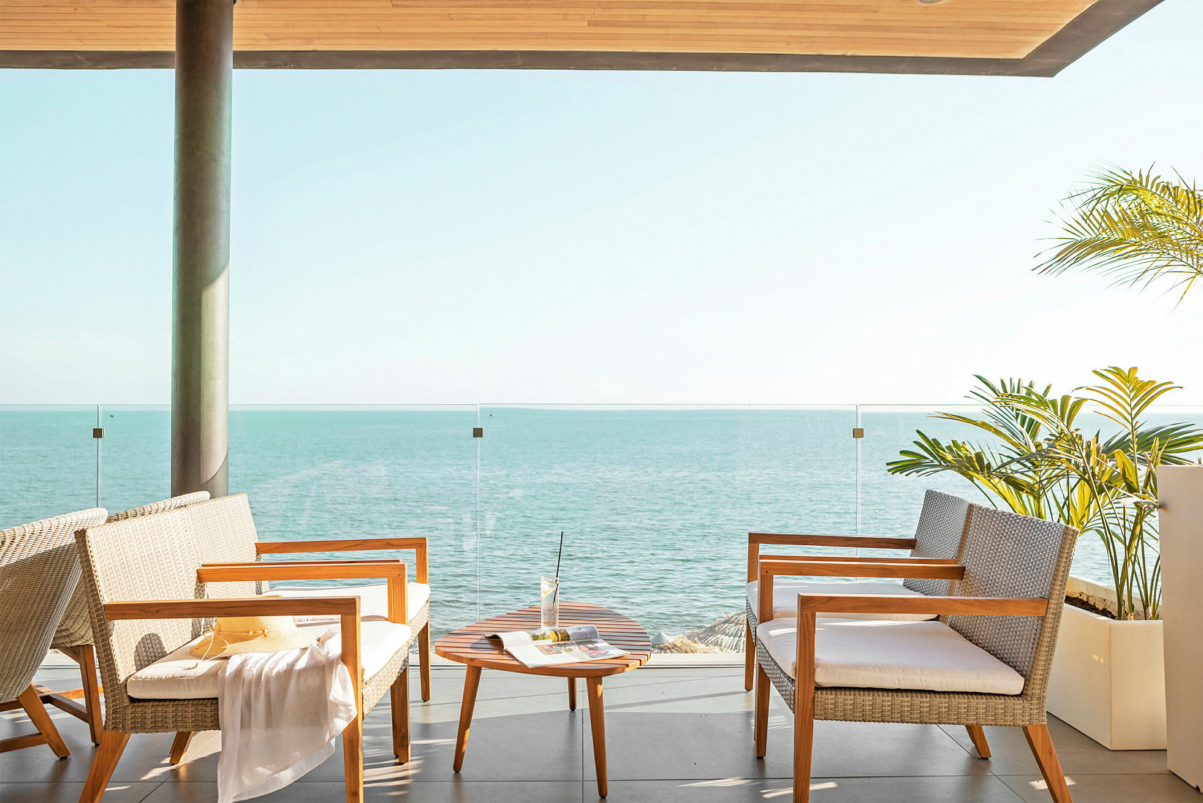 Terrasse med siddepladser, et lille bord og udsigt over havet. (AI-genereret tekst)