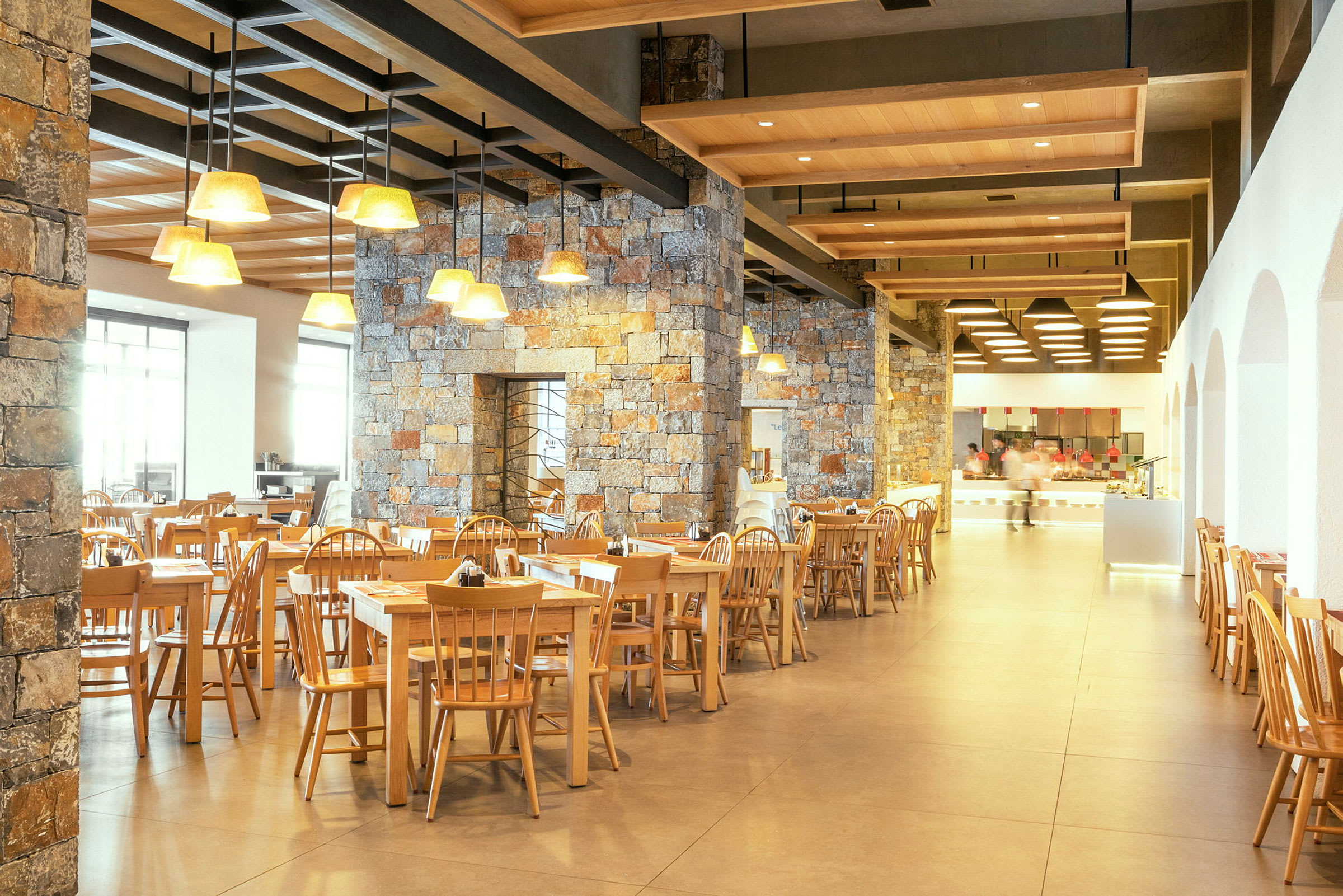 Restaurant med træstole og borde samt stenvægge og loftslamper. (AI-genereret tekst)