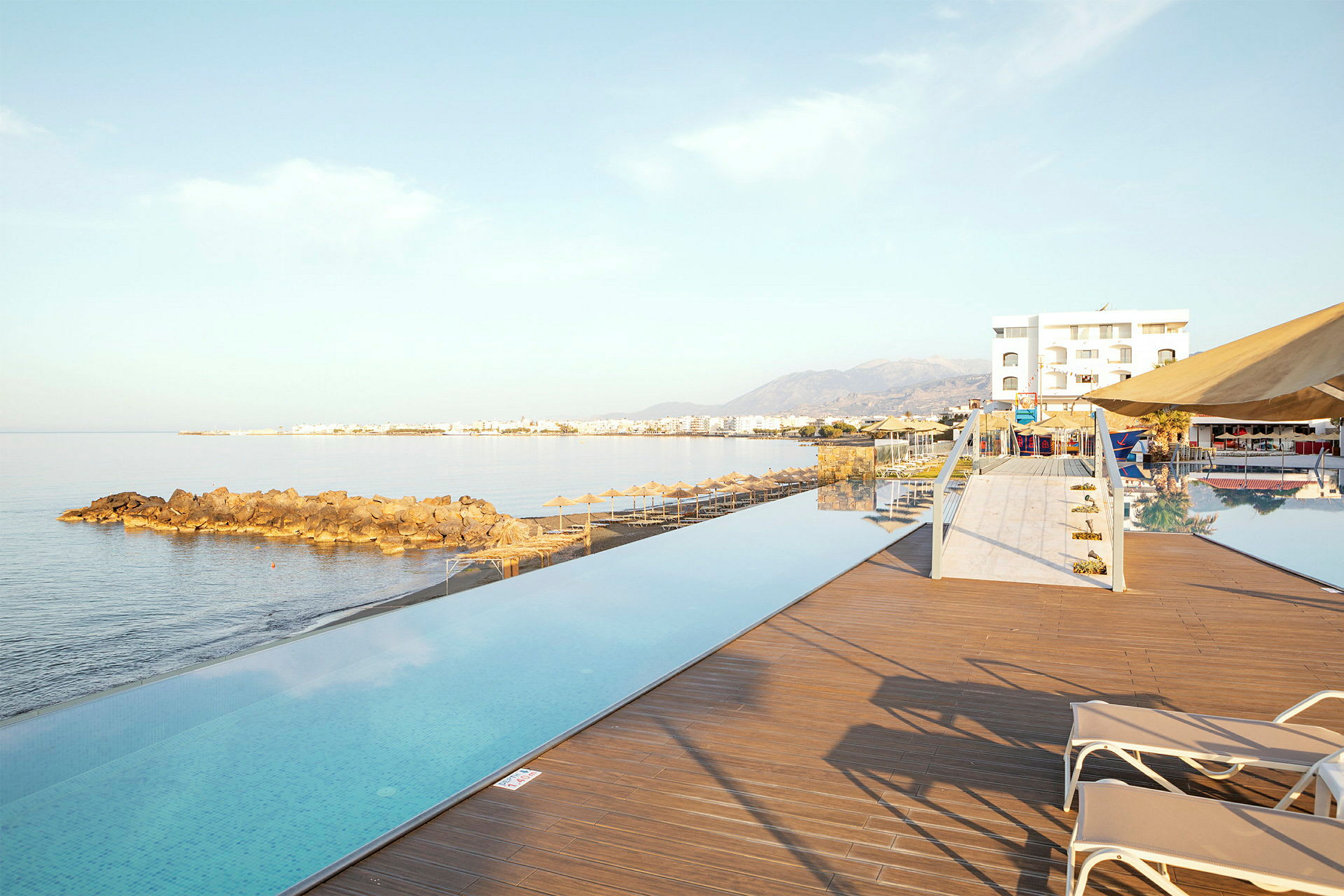 Infinity-pool ved havet med udsigt over kysten og bjergene. (AI-genereret tekst)