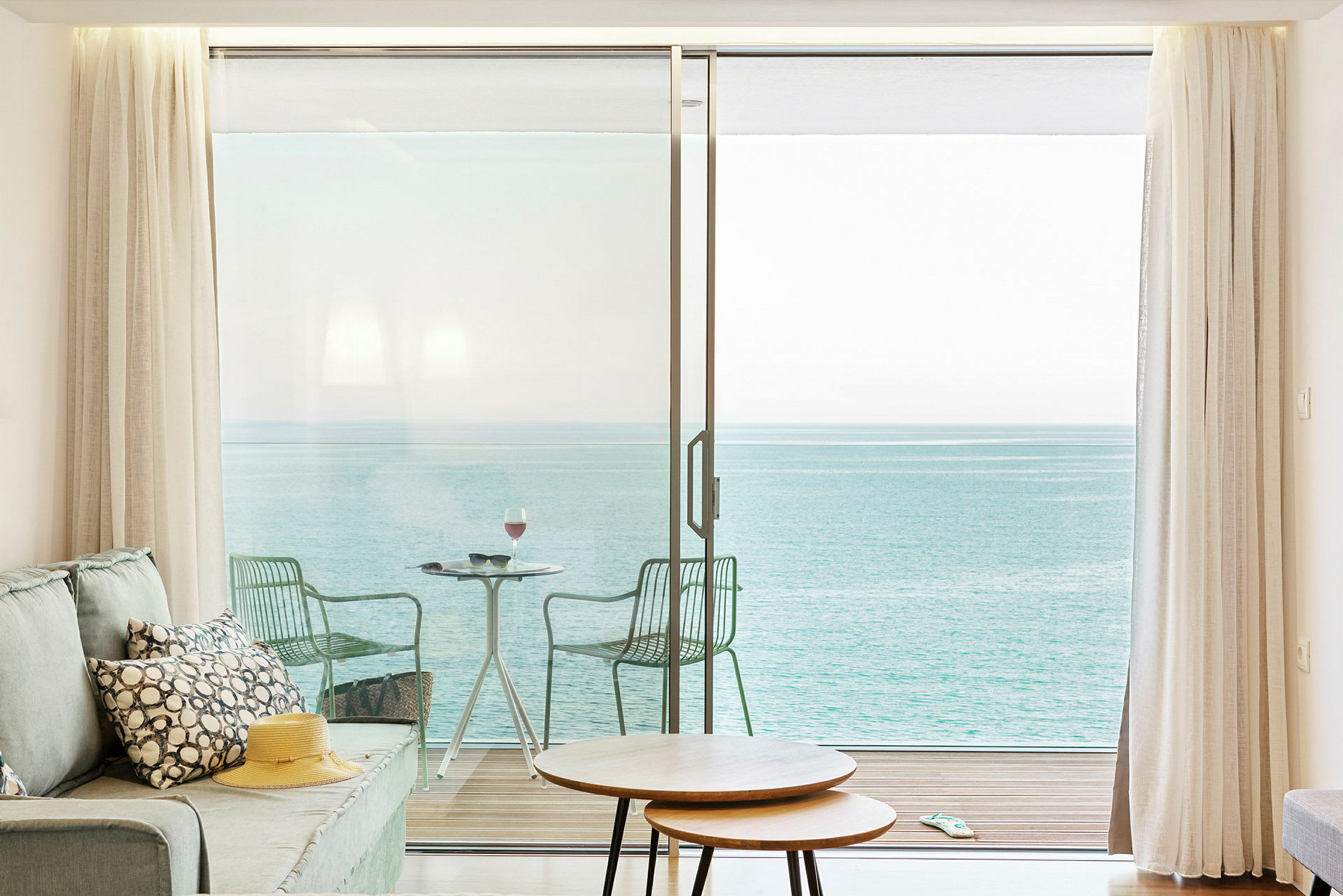 Stue med udsigt over havet gennem store glasskydedøre, der fører ud til en balkon. (AI-genereret tekst)