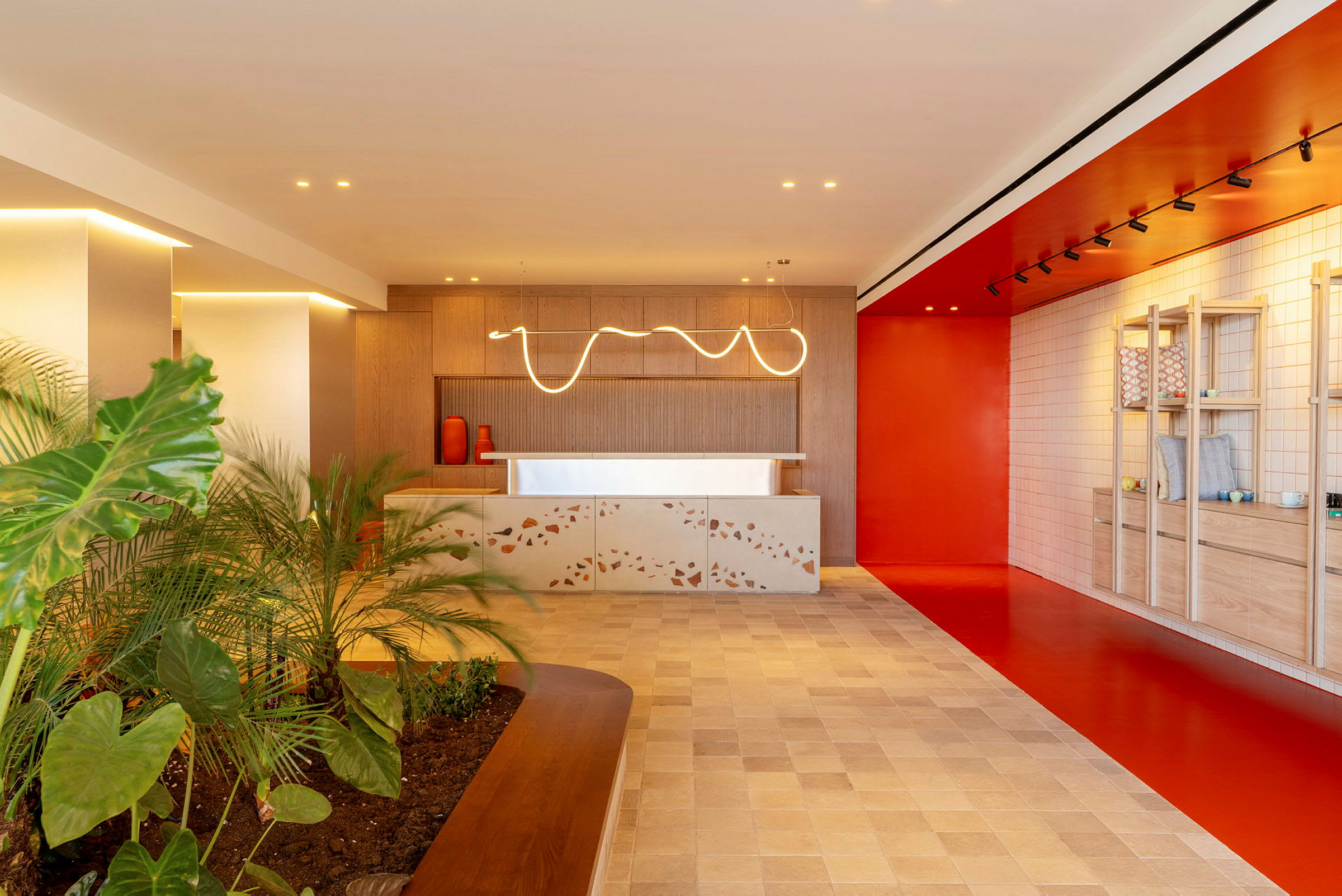 En moderne lobby med en receptionsdisk, orange accenter og planter. (AI-genereret tekst)