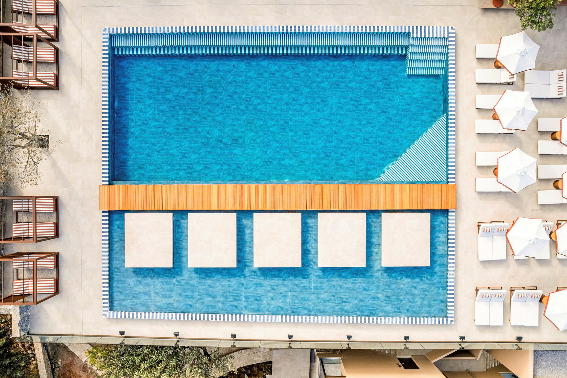 En moderne swimmingpool omgivet af solsenge og parasoller. (AI-genereret tekst)