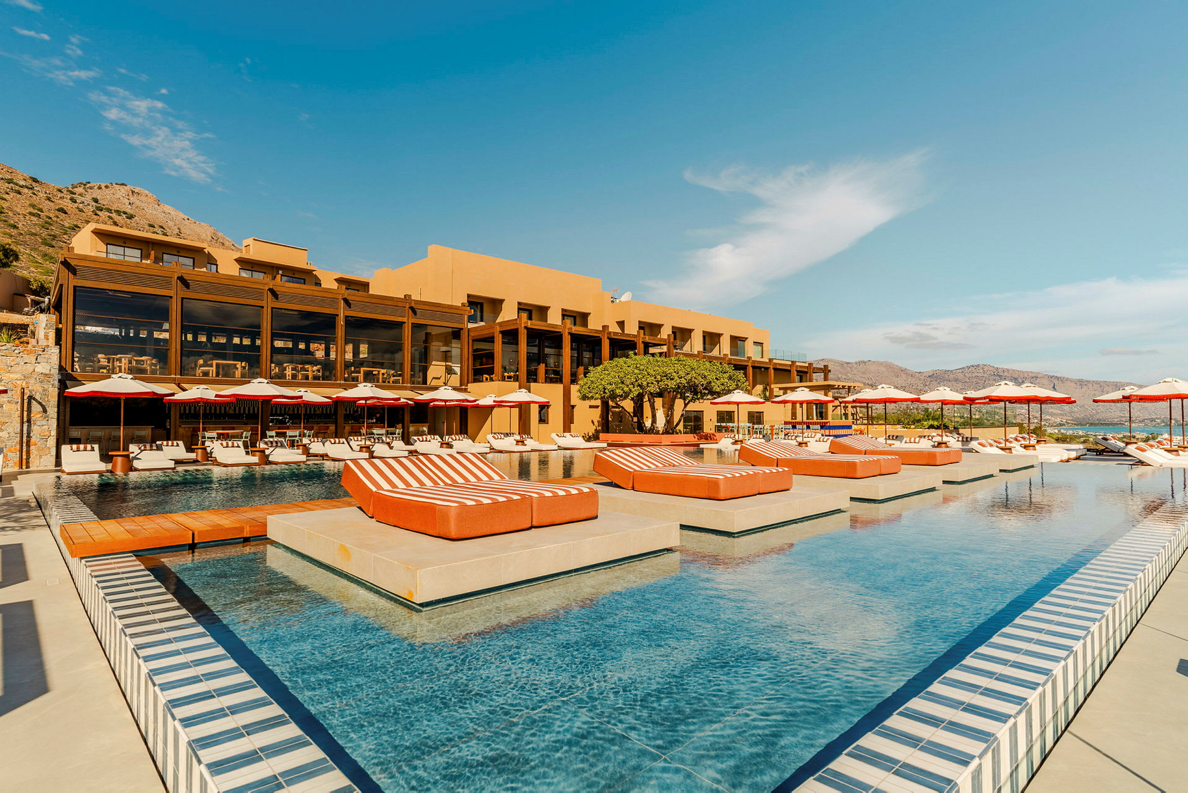 Billede af en resort med pool, liggestole og parasoller. (AI-genereret tekst)