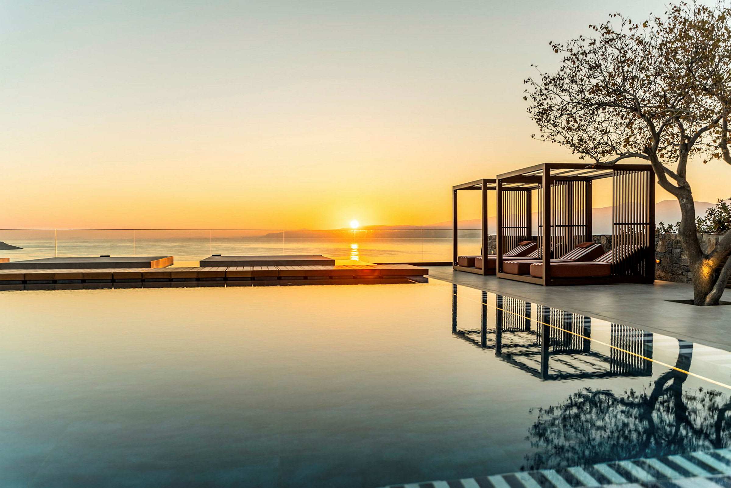Udendørs pool med solnedgang i baggrunden. (AI-genereret tekst)