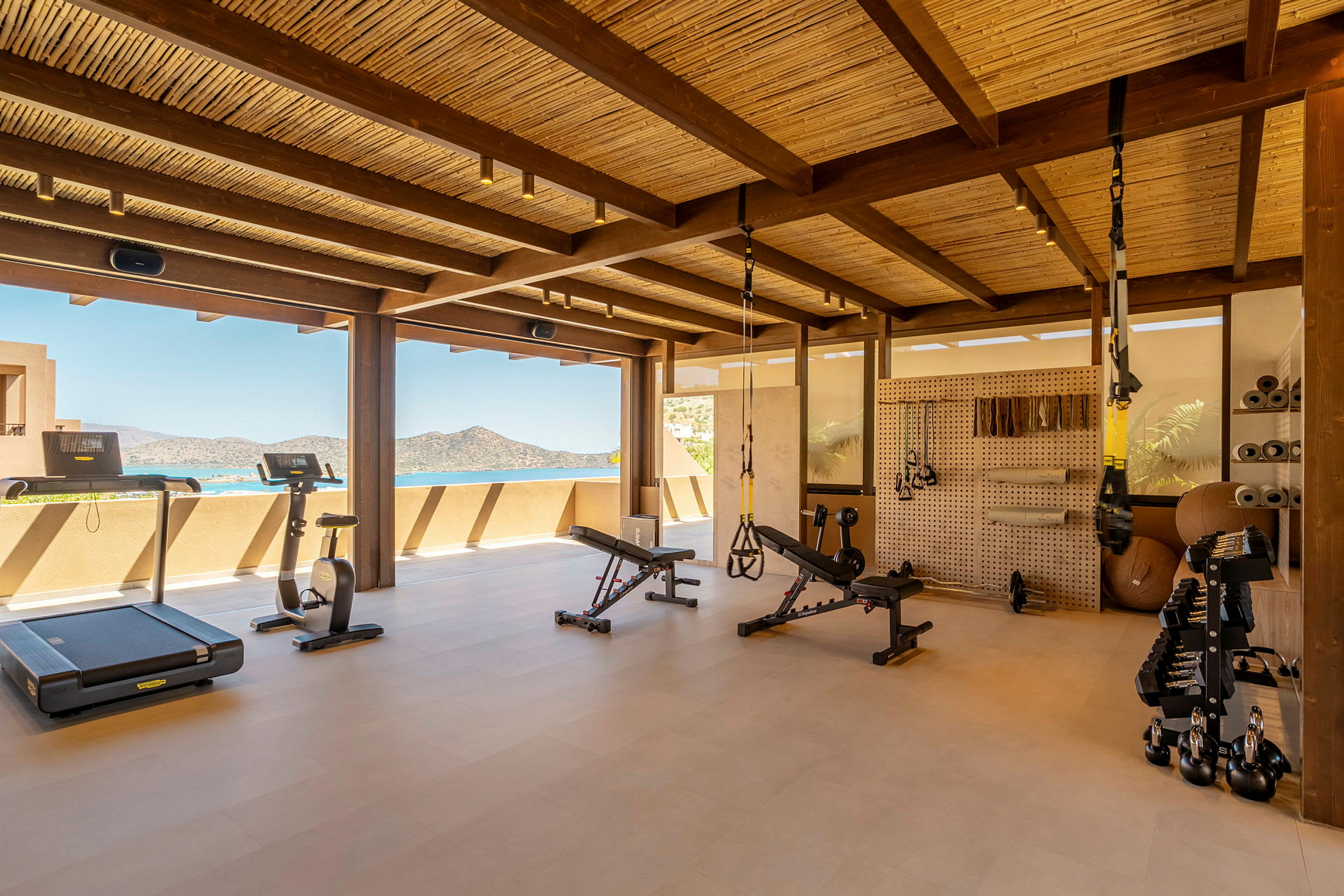Et moderne fitnesscenter med træningsudstyr og udsigt over havet. (AI-genereret tekst)