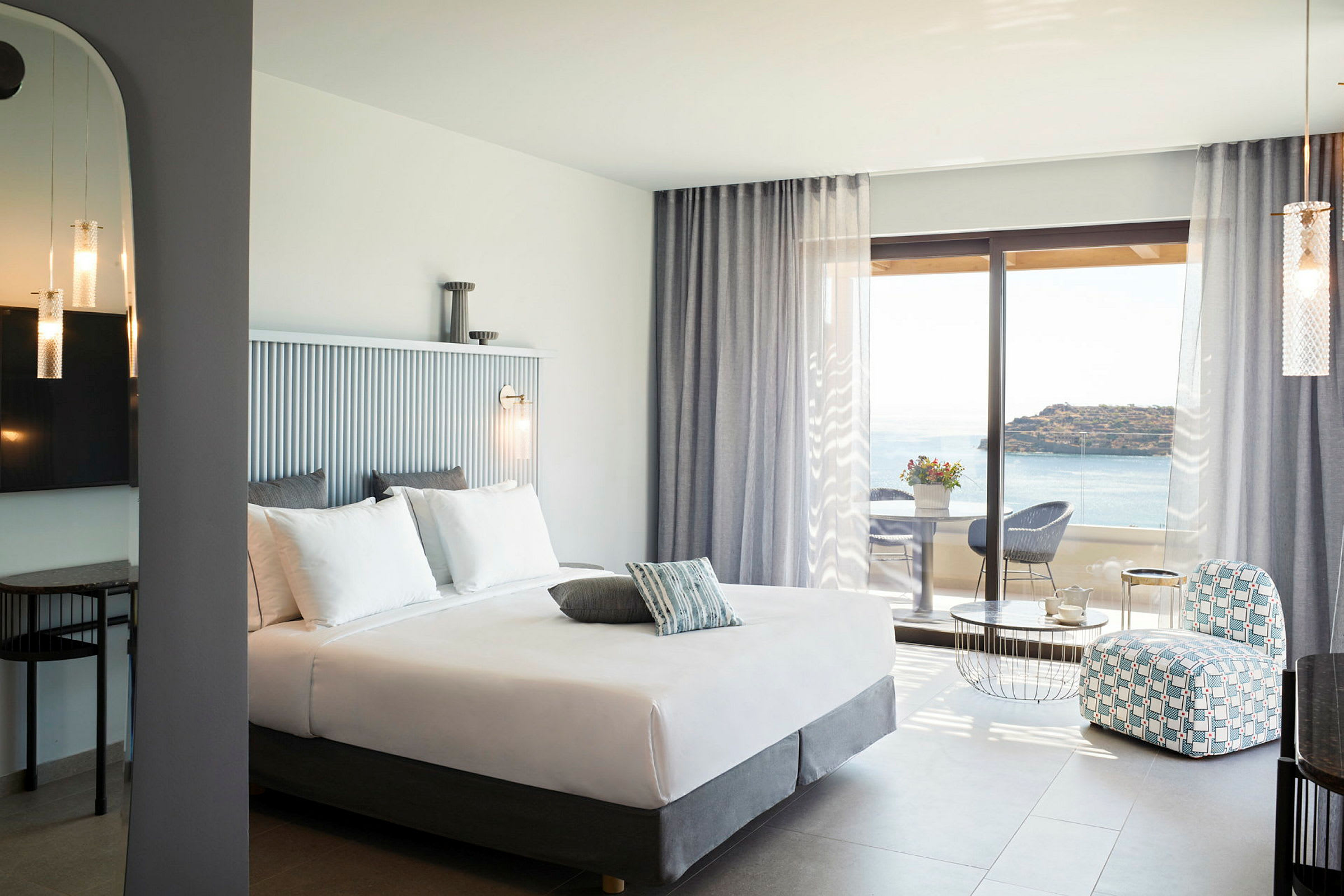 Hotelværelse med dobbeltseng, siddeområde og udsigt over havet. (AI-genereret tekst)