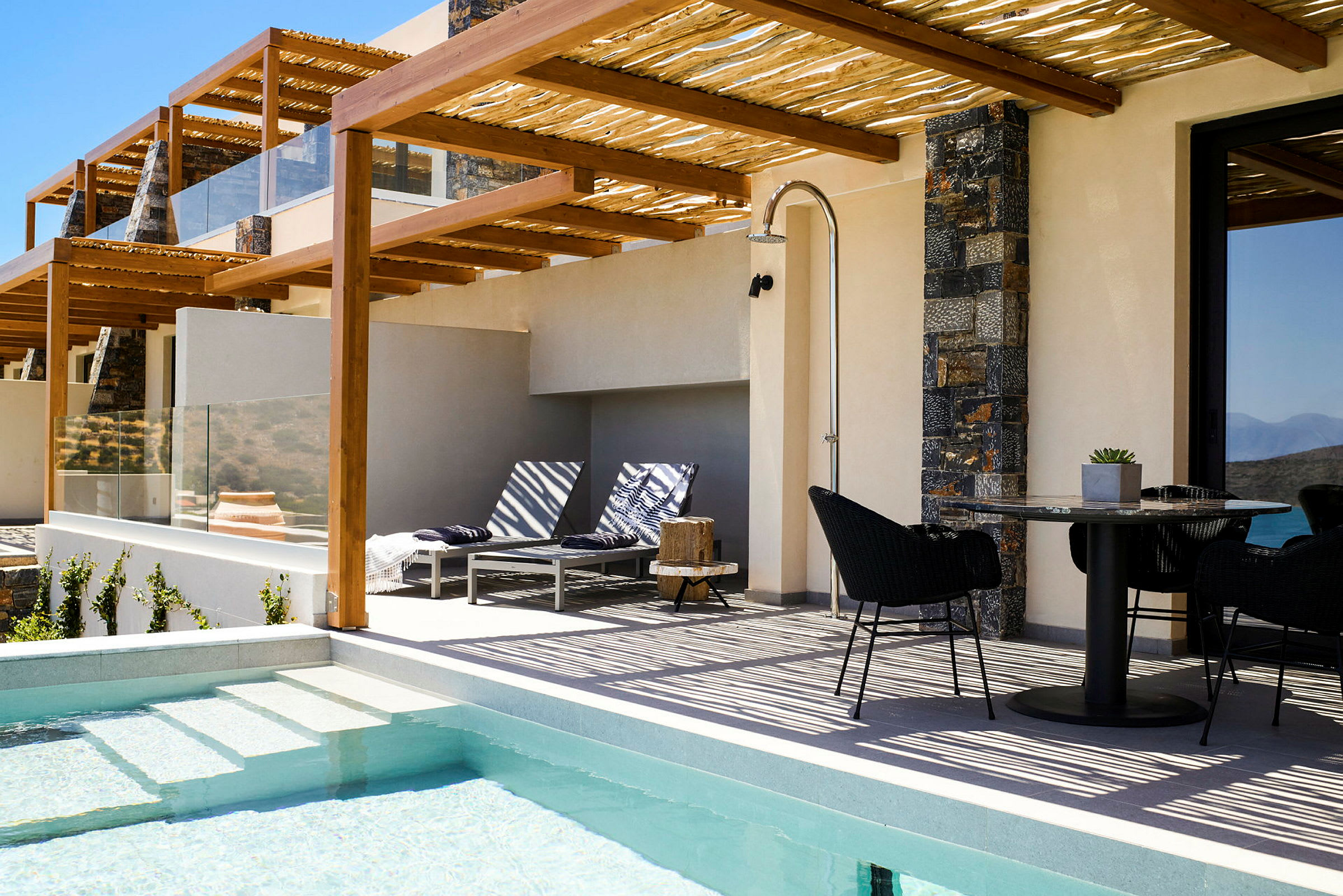 Udendørsområde med pool, liggestole og spisebord under en pergola. (AI-genereret tekst)