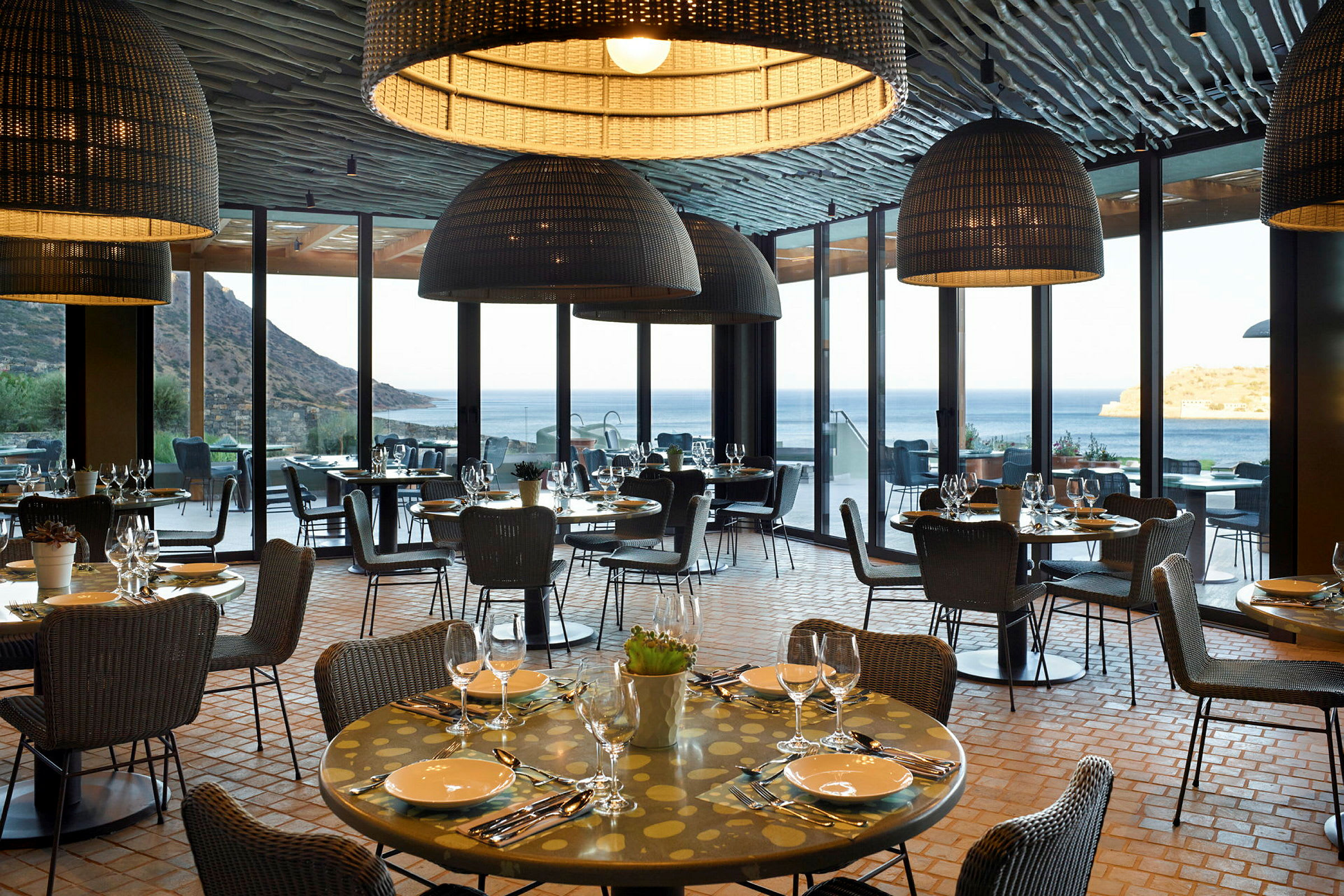 En restaurant med dækkede borde beliggende med udsigt over havet. (AI-genereret tekst)