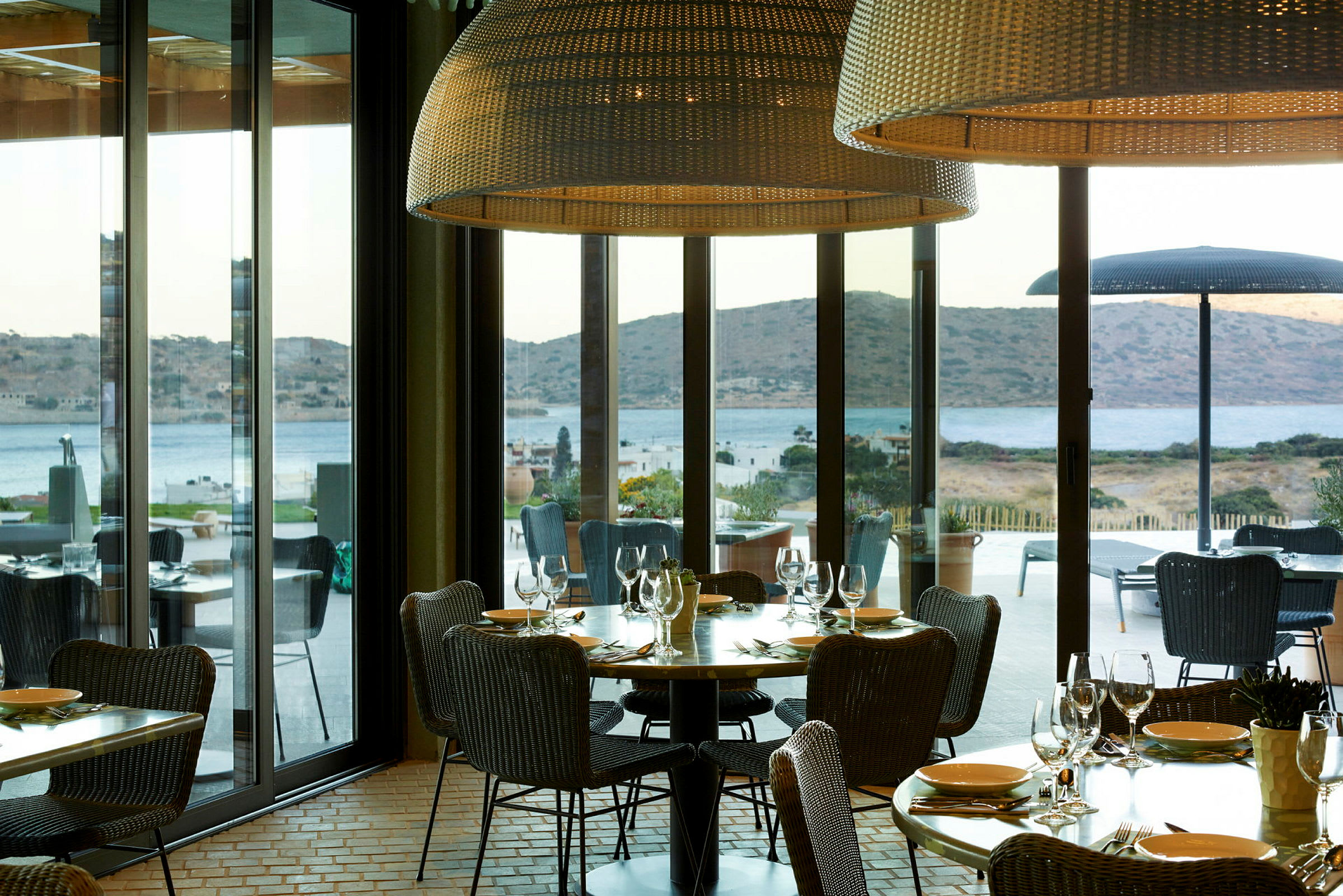 Restaurant med udsigt over havet og bjerge gennem store vinduer. (AI-genereret tekst)
