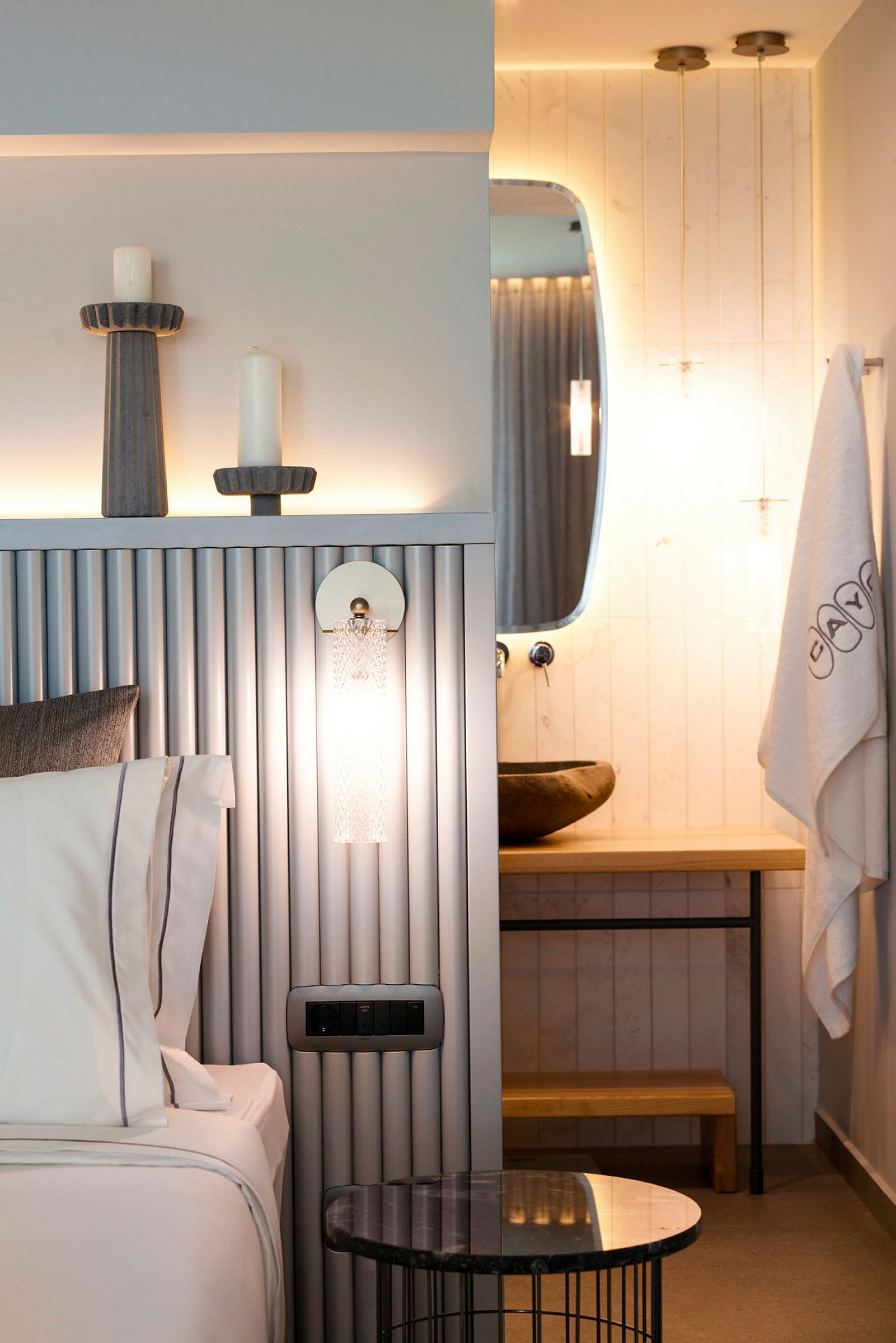 Et moderne hotelværelse med en seng, et dekorativt bord og et badeværelse med et spejl. (AI-genereret tekst)