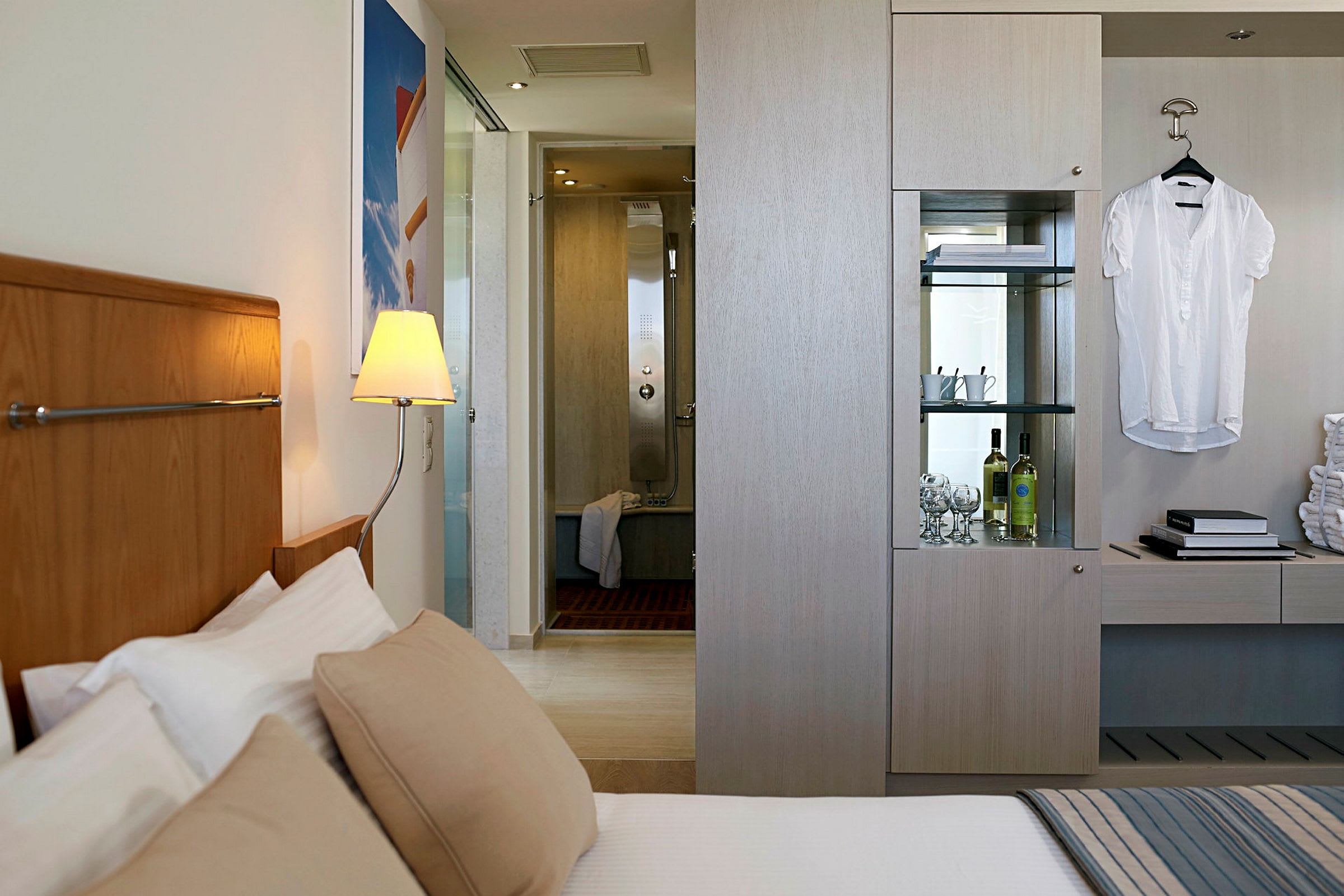 Et moderne hotelværelse med en seng, en læselampe, et skab og et badeværelse i baggrunden. (AI-genereret tekst)