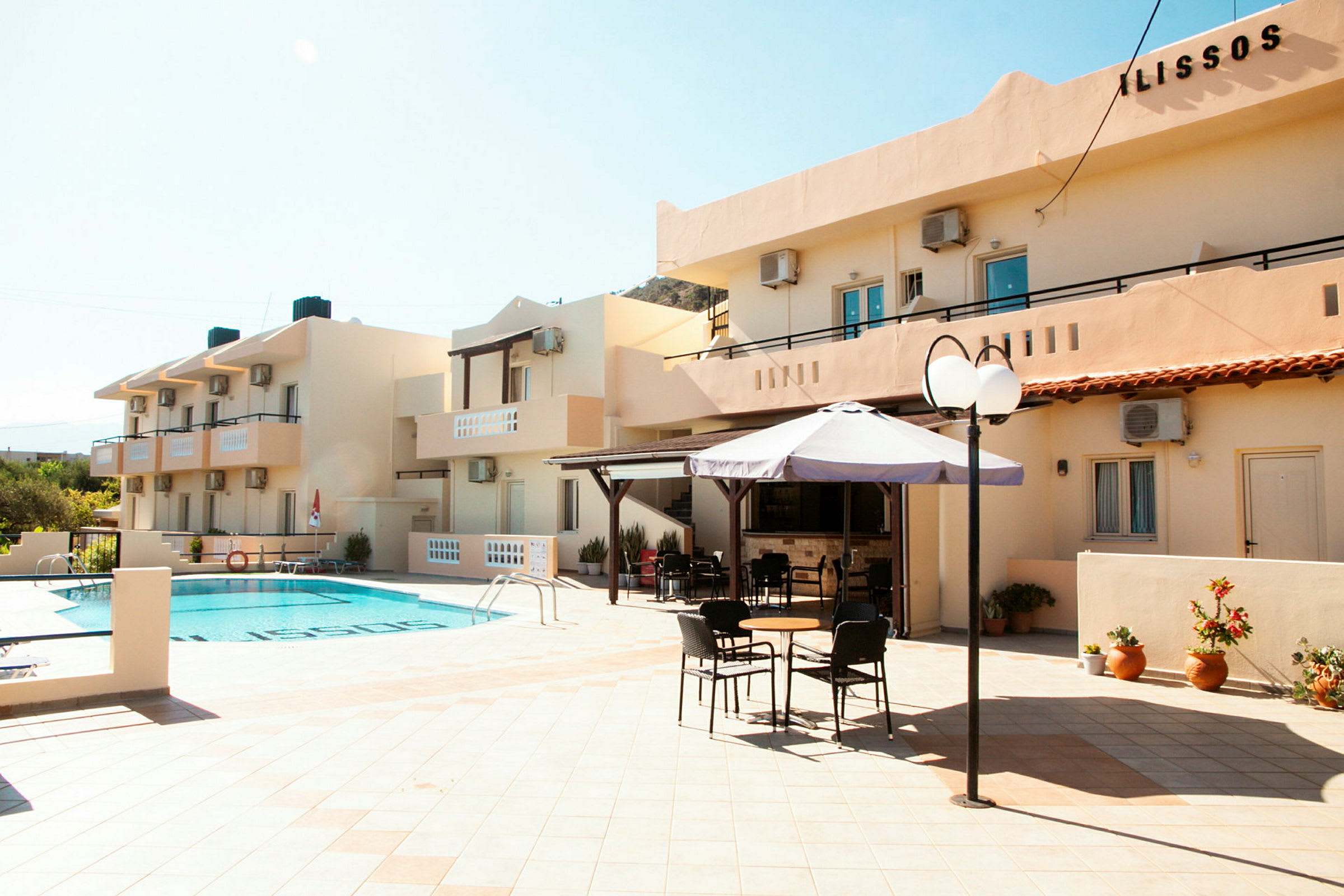 Udendørsområde ved hotel med en pool, parasol og siddepladser. (AI-genereret tekst)