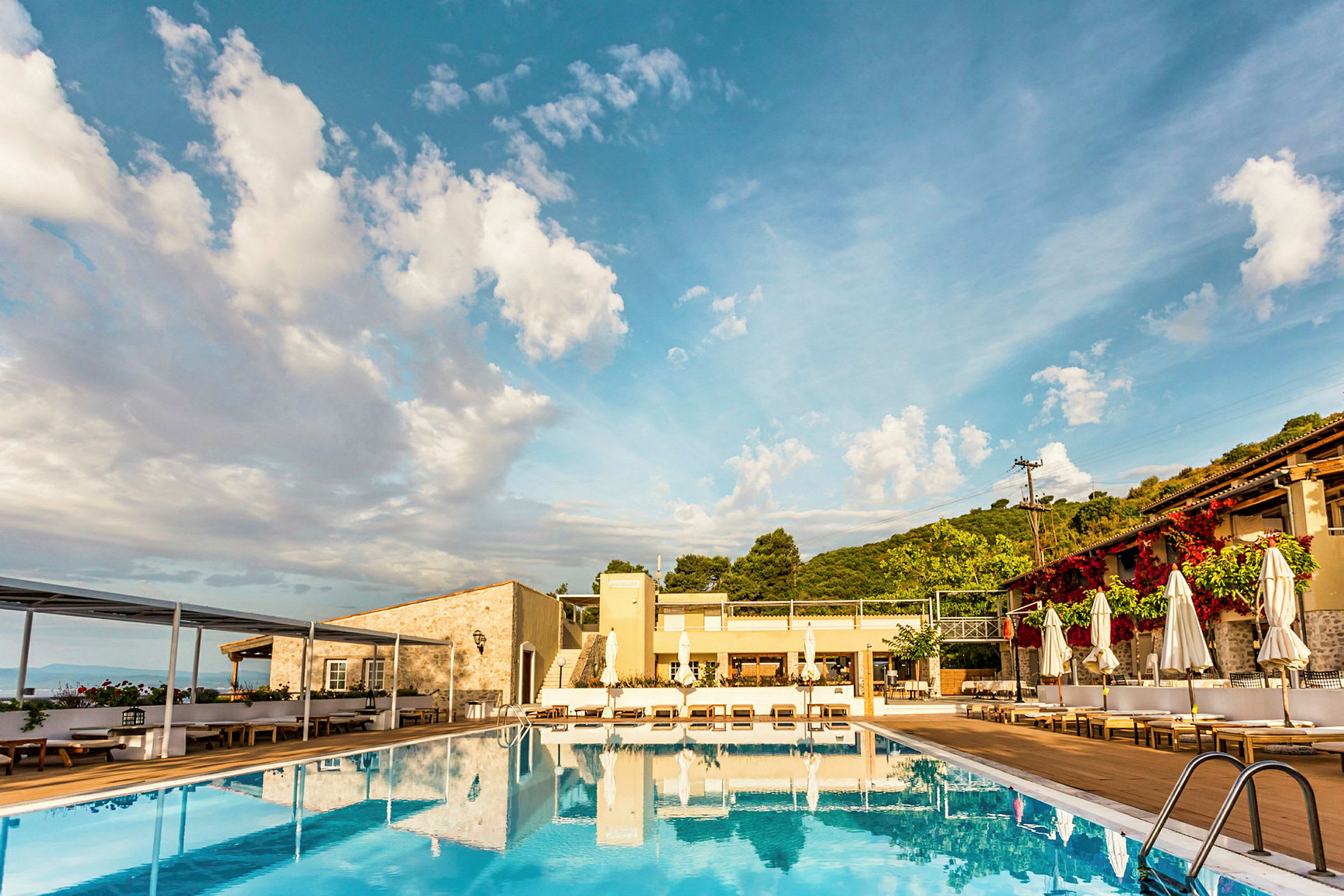 Udendørs swimmingpool ved et hotel med bjerge i baggrunden. (AI-genereret tekst)