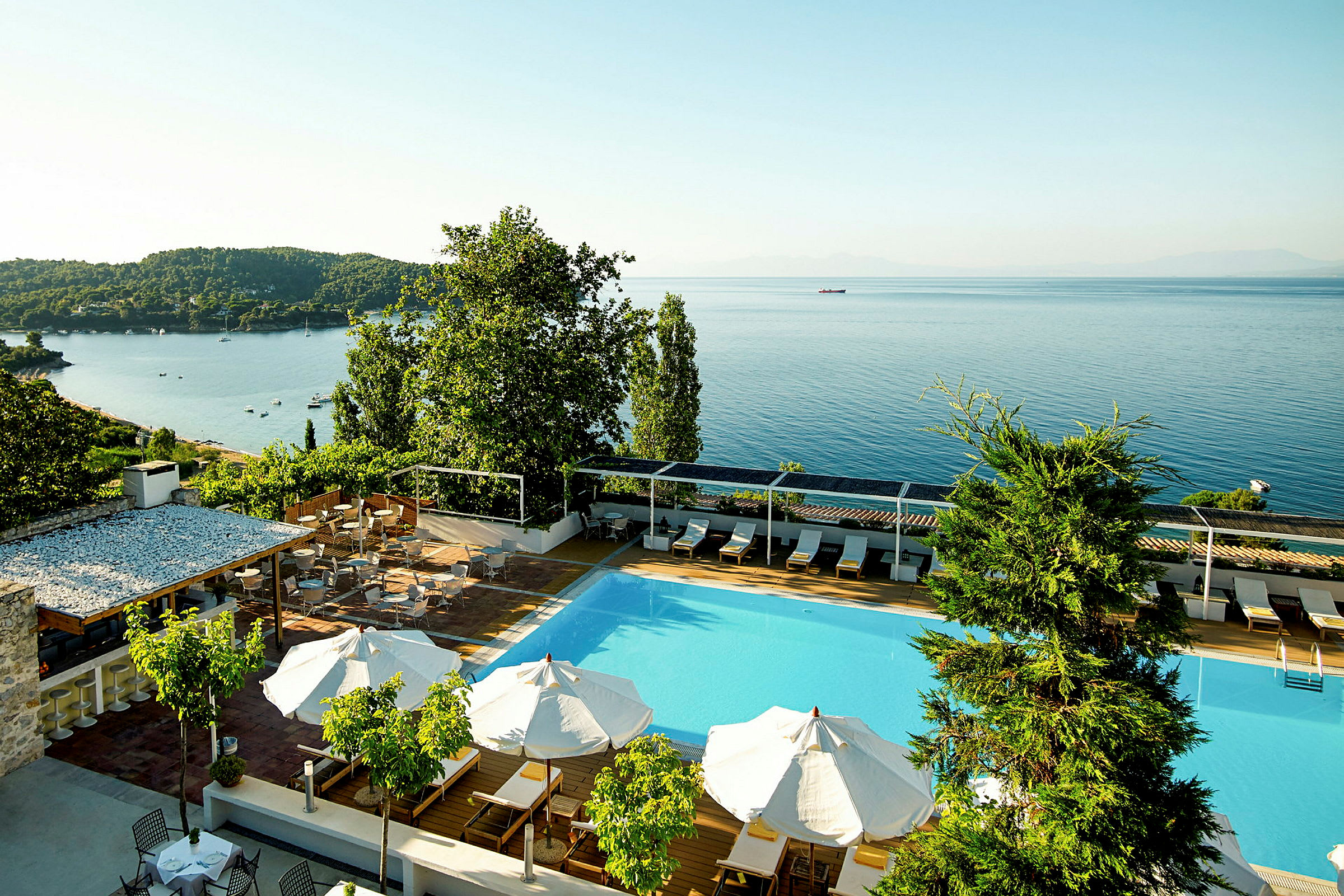 Hotelpool med udsigt over havet og frodige omgivelser. (AI-genereret tekst)