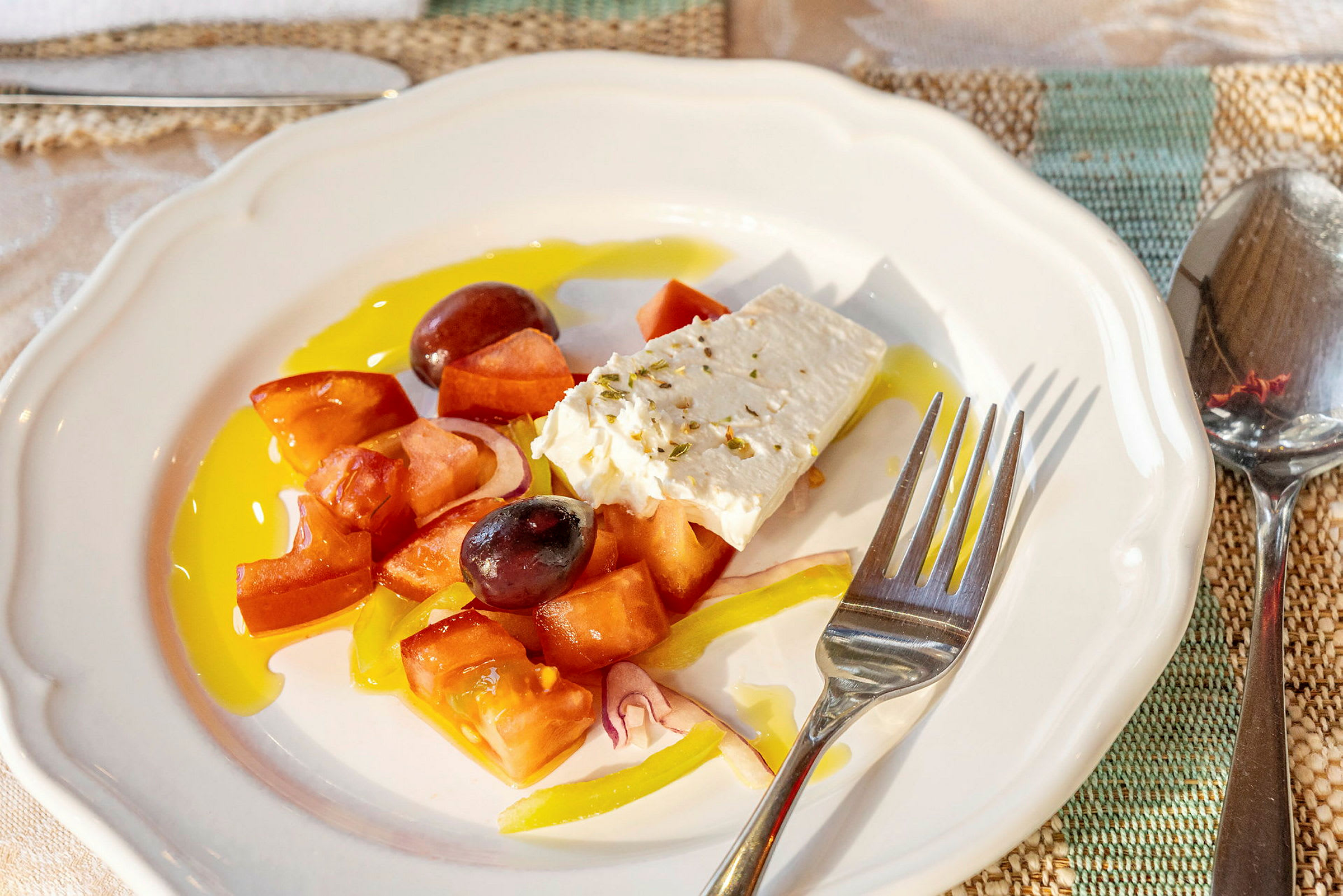 En tallerken med græsk salat indeholdende tomater, fetaost, oliven og peberfrugt. (AI-genereret tekst)