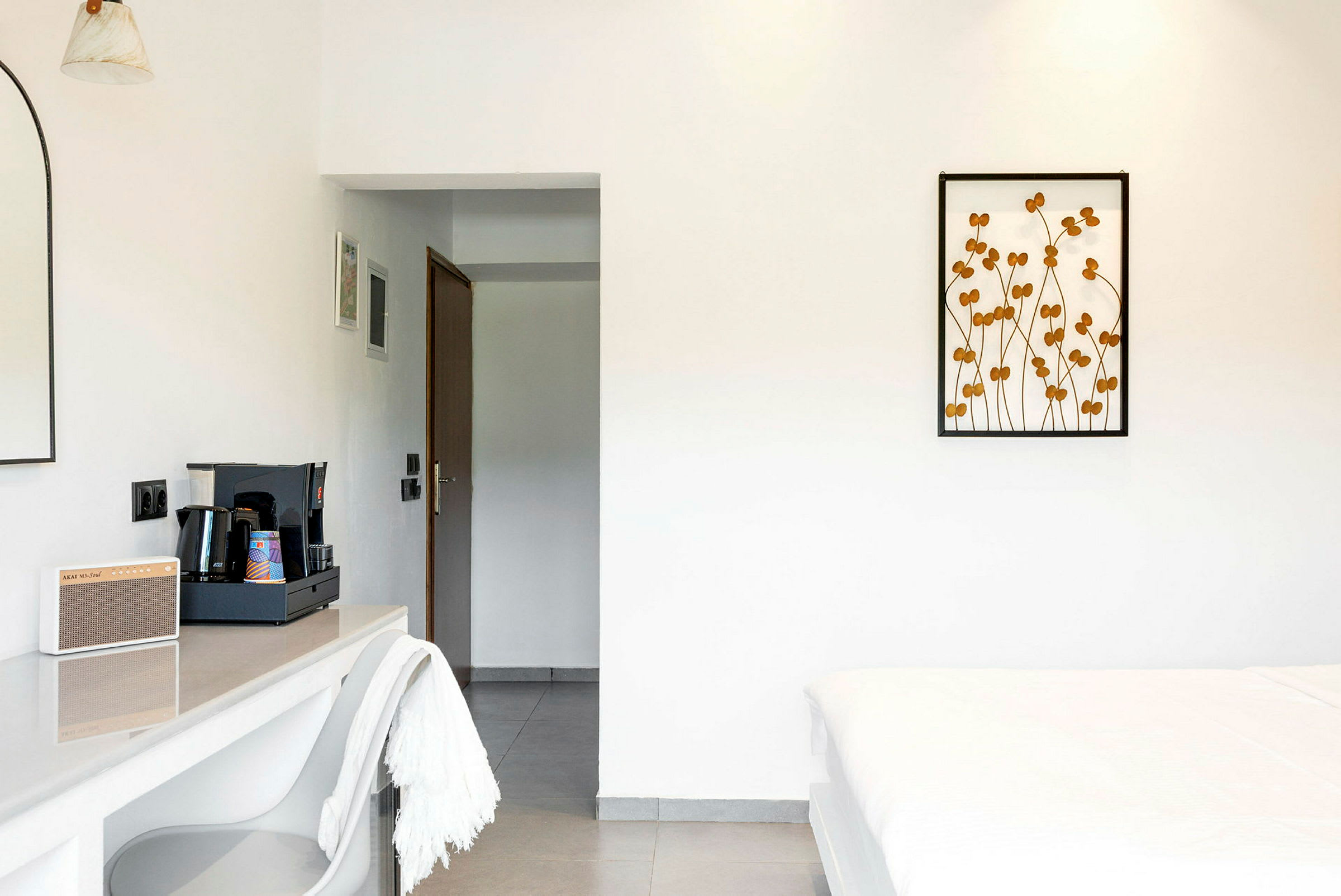 Et hotelværelse med minimalistisk indretning, herunder en kaffestation og en seng. (AI-genereret tekst)