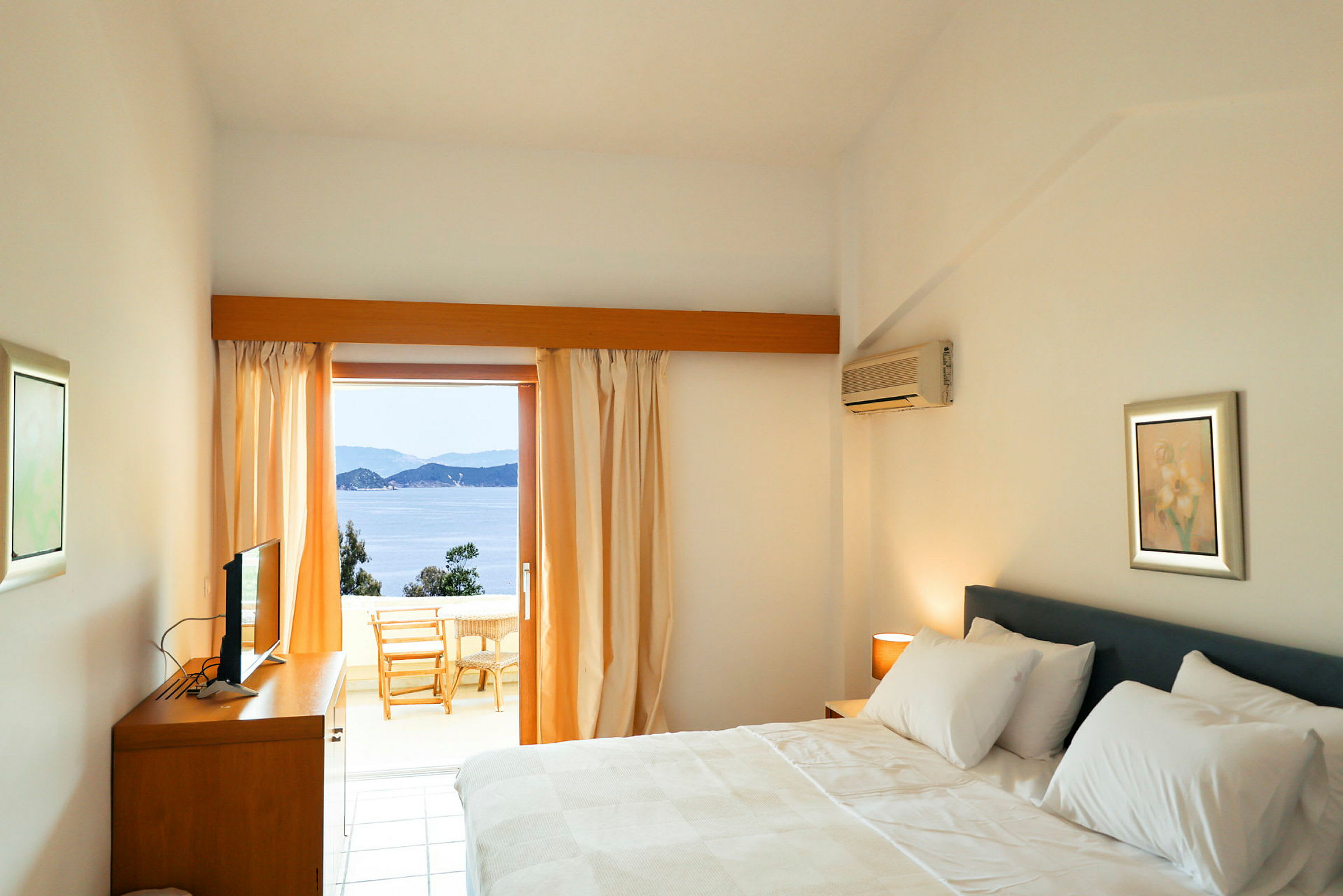 Hotelværelse med en dobbelt seng og udsigt over havet fra en altan. (AI-genereret tekst)
