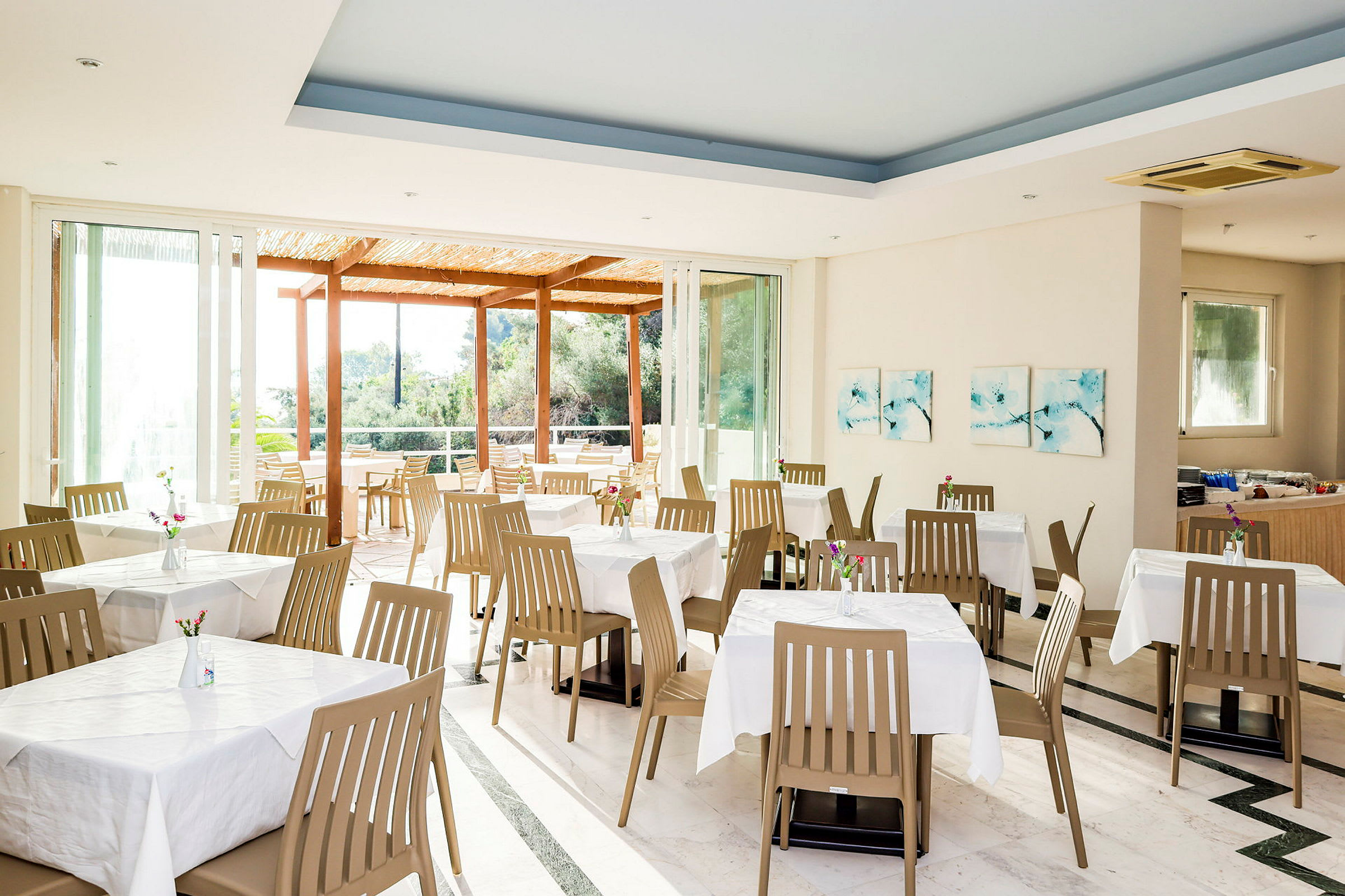 Restaurant med dækkede borde og stole samt store vinduer med udsigt. (AI-genereret tekst)