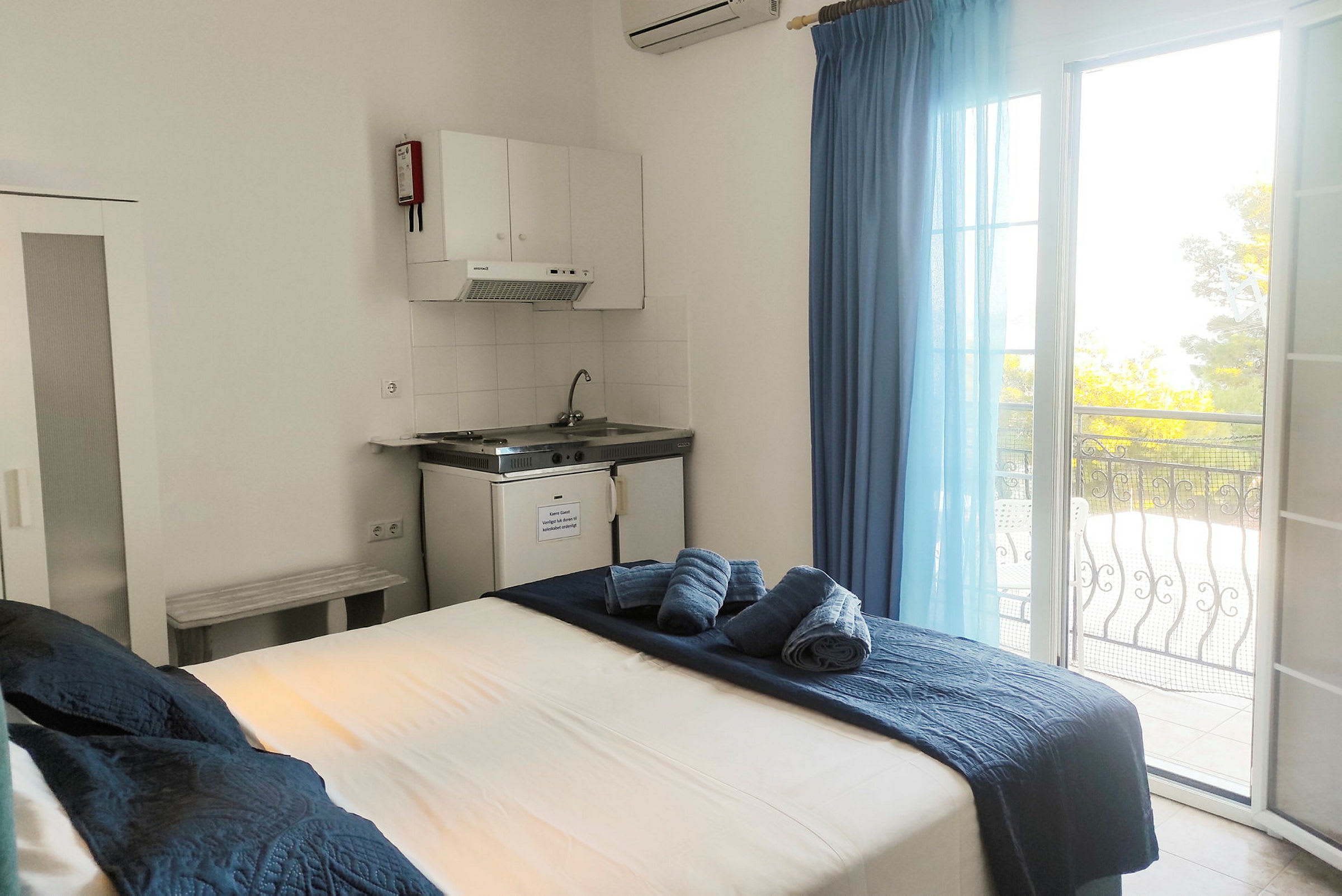 Hotelværelse med seng, køkkenområde og balkon med udsigt. (AI-genereret tekst)