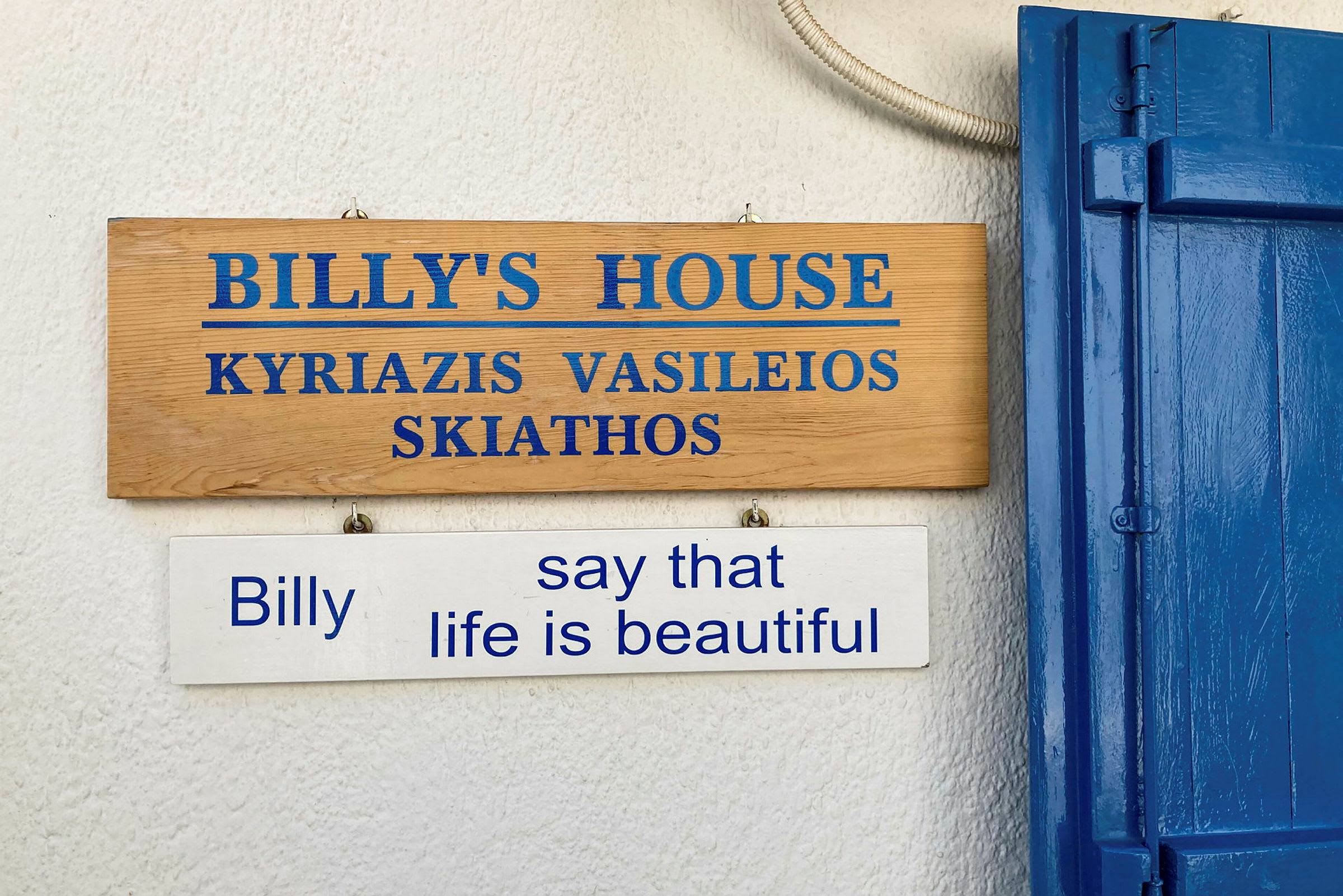 Træskilt der markerer 'Billy's House' og et hvidt skilt under der siger "Billy say that life is beautiful". (AI-genereret tekst)