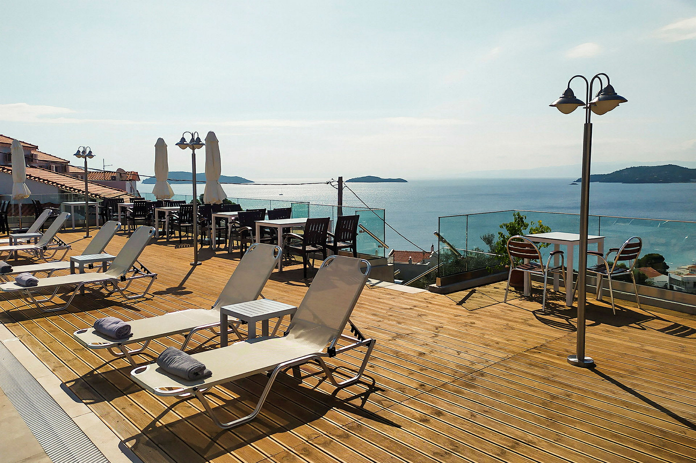 En terrasse med liggestole, borde og stole samt udsigt over havet. (AI-genereret tekst)